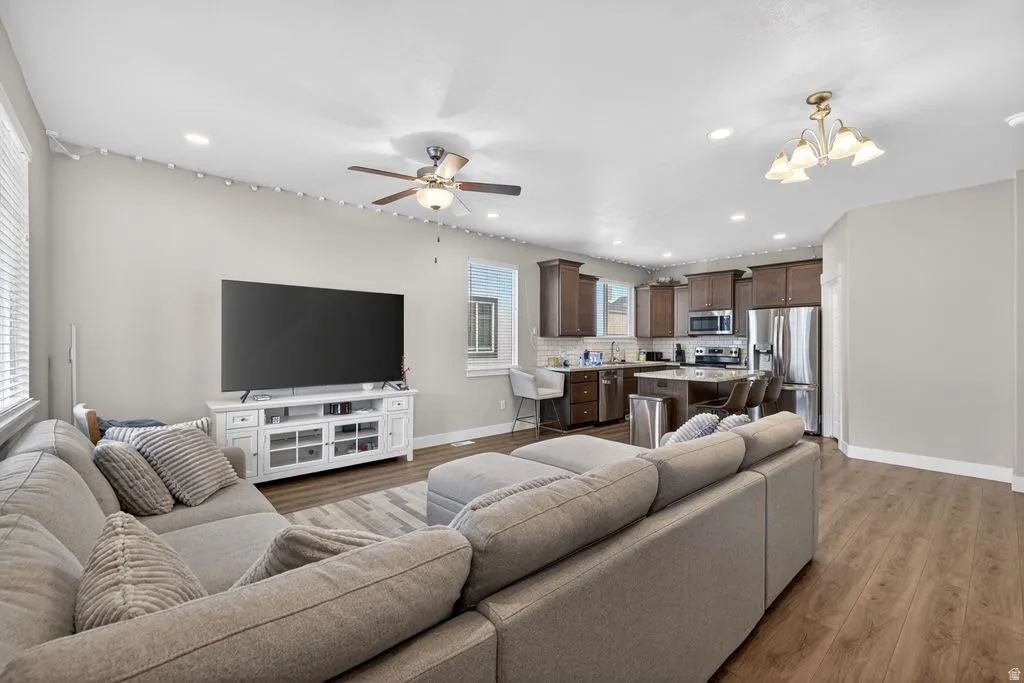 Living room with light wood finished floors, a chandelier, and ceiling fan