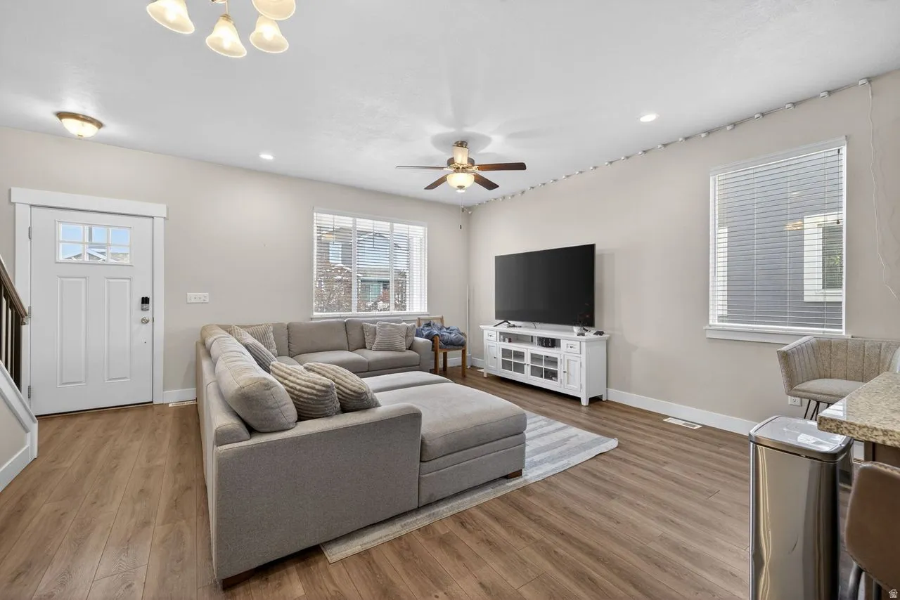 Living room featuring wood finished floors, a ceiling fan, and hanging lights