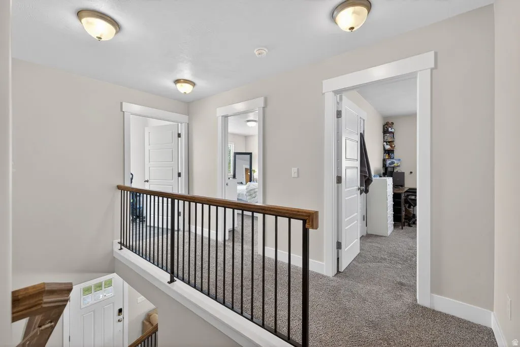 Corridor featuring carpet flooring and an upstairs landing