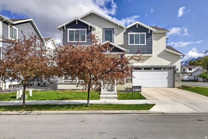 Craftsman house featuring stucco siding, concrete driveway, a front lawn, and an attached garage