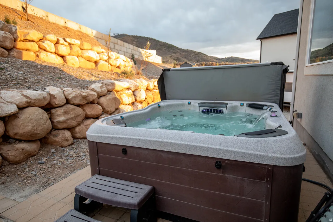 View of patio with a mountain view and a hot tub