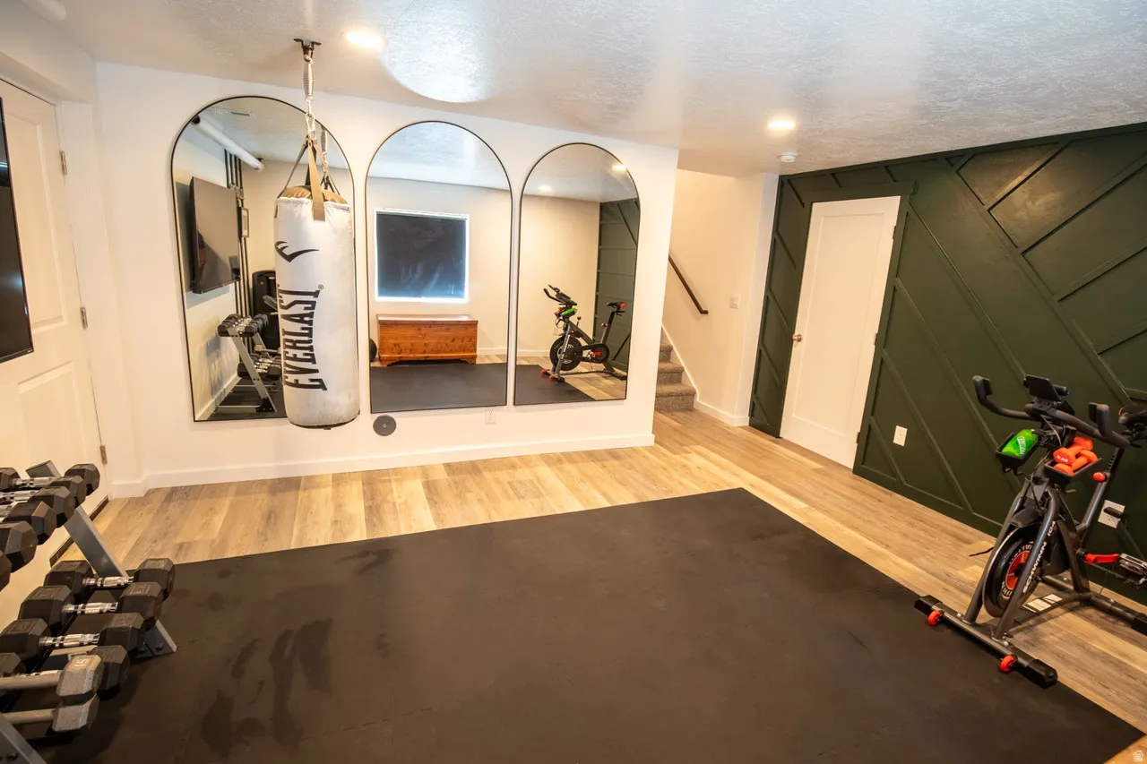 Exercise room with light wood-type flooring and a decorative wall