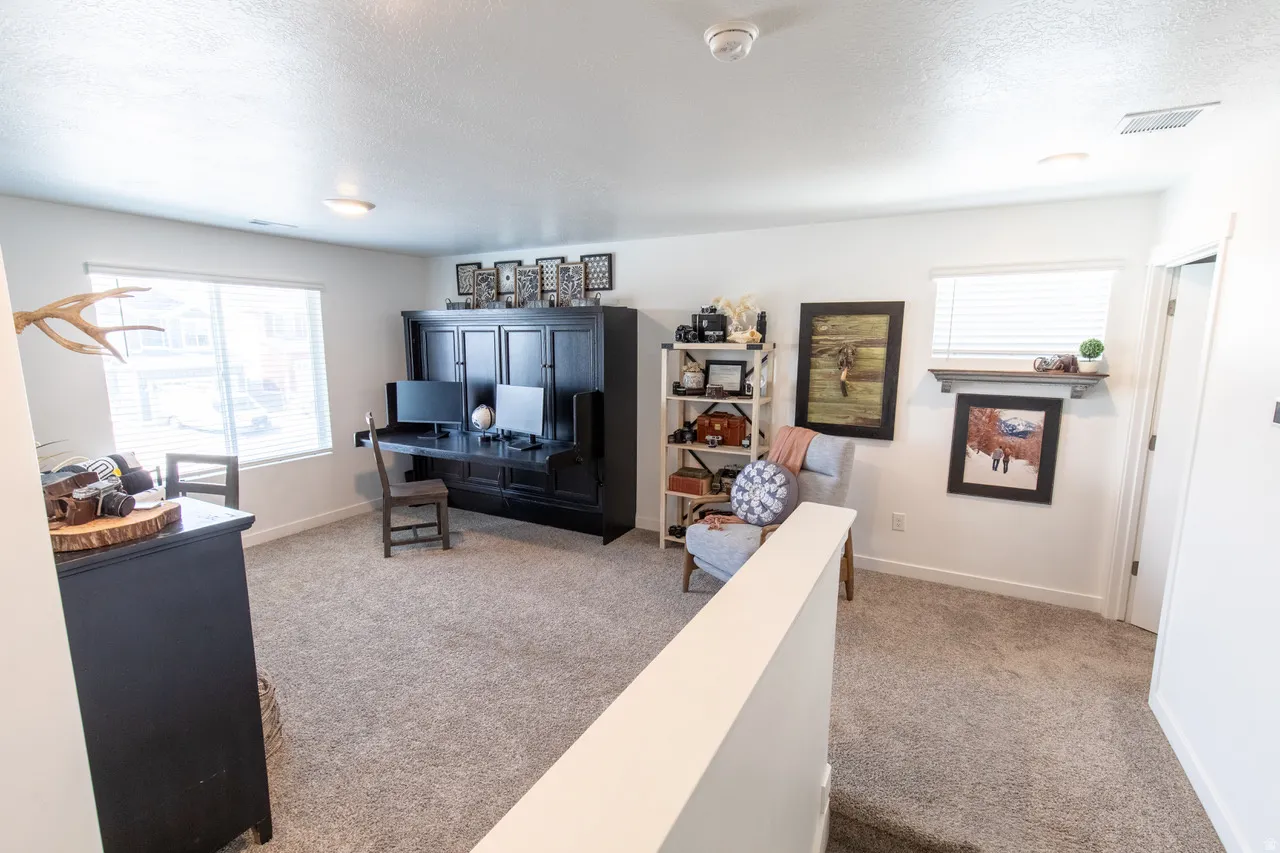 Office area featuring light carpet and a textured ceiling