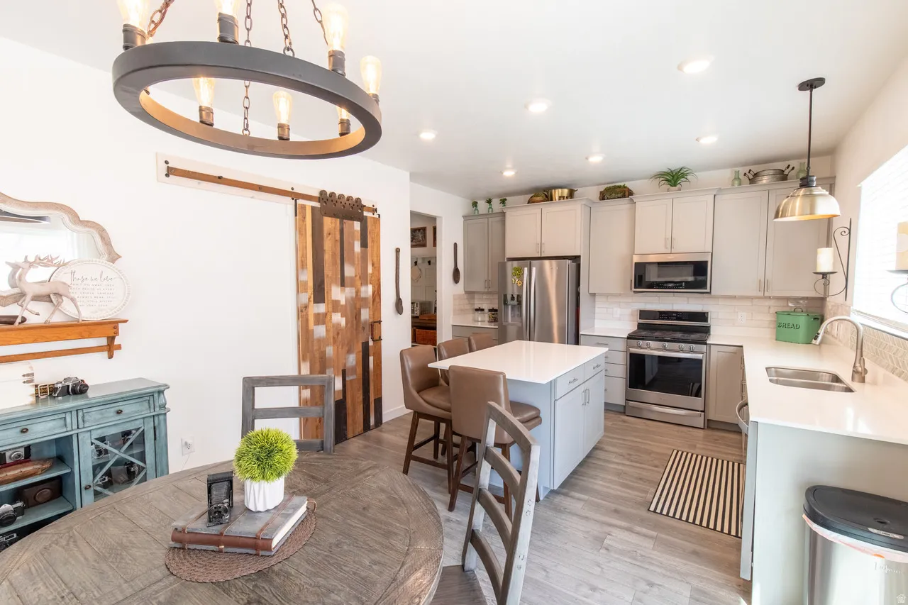 Kitchen featuring stainless steel appliances, a center island, a kitchen breakfast bar, light wood-style floors, and backsplash
