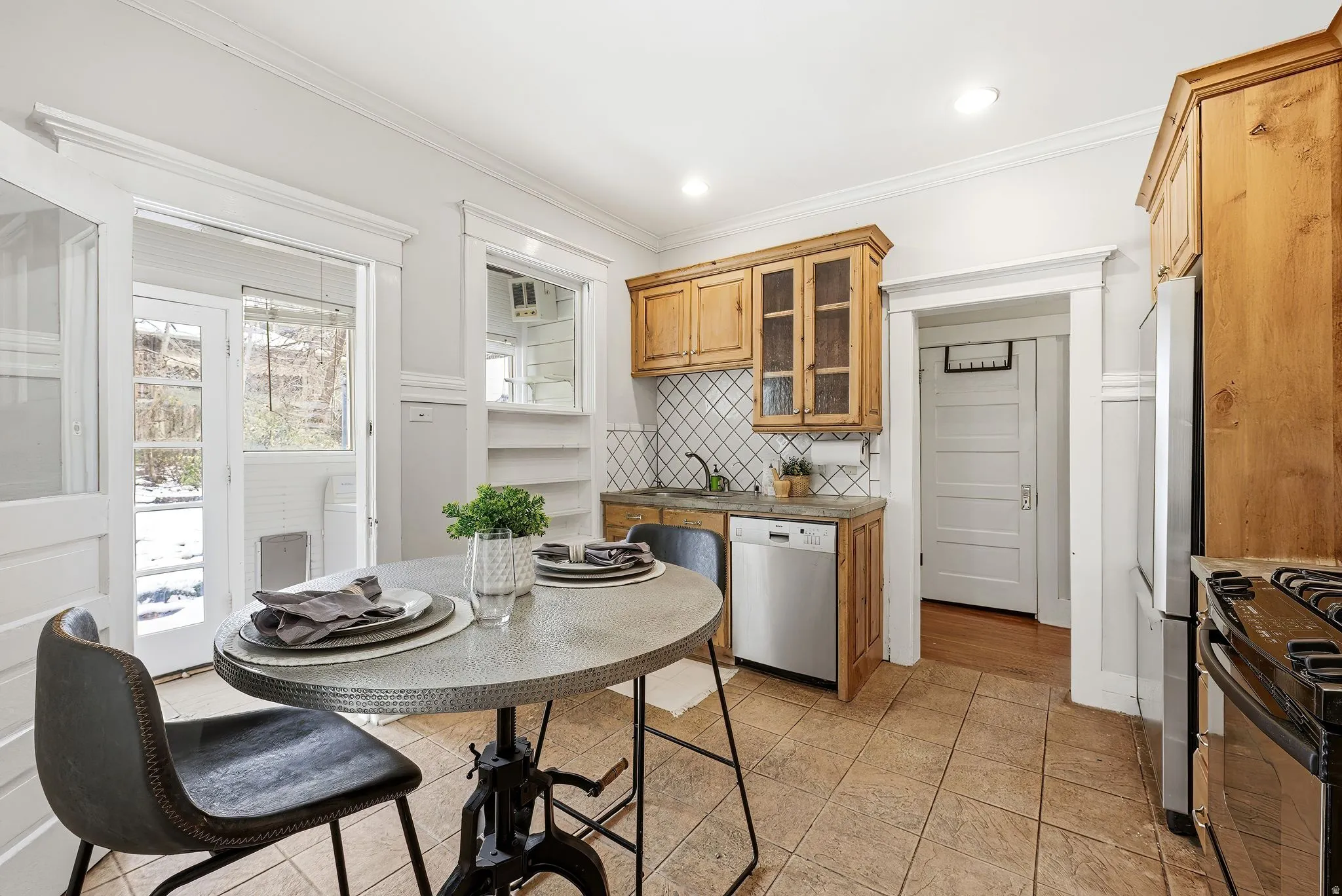 Kitchen with glass insert cabinets, stainless steel appliances, dark countertops, wood finish cabinets, and ornamental molding