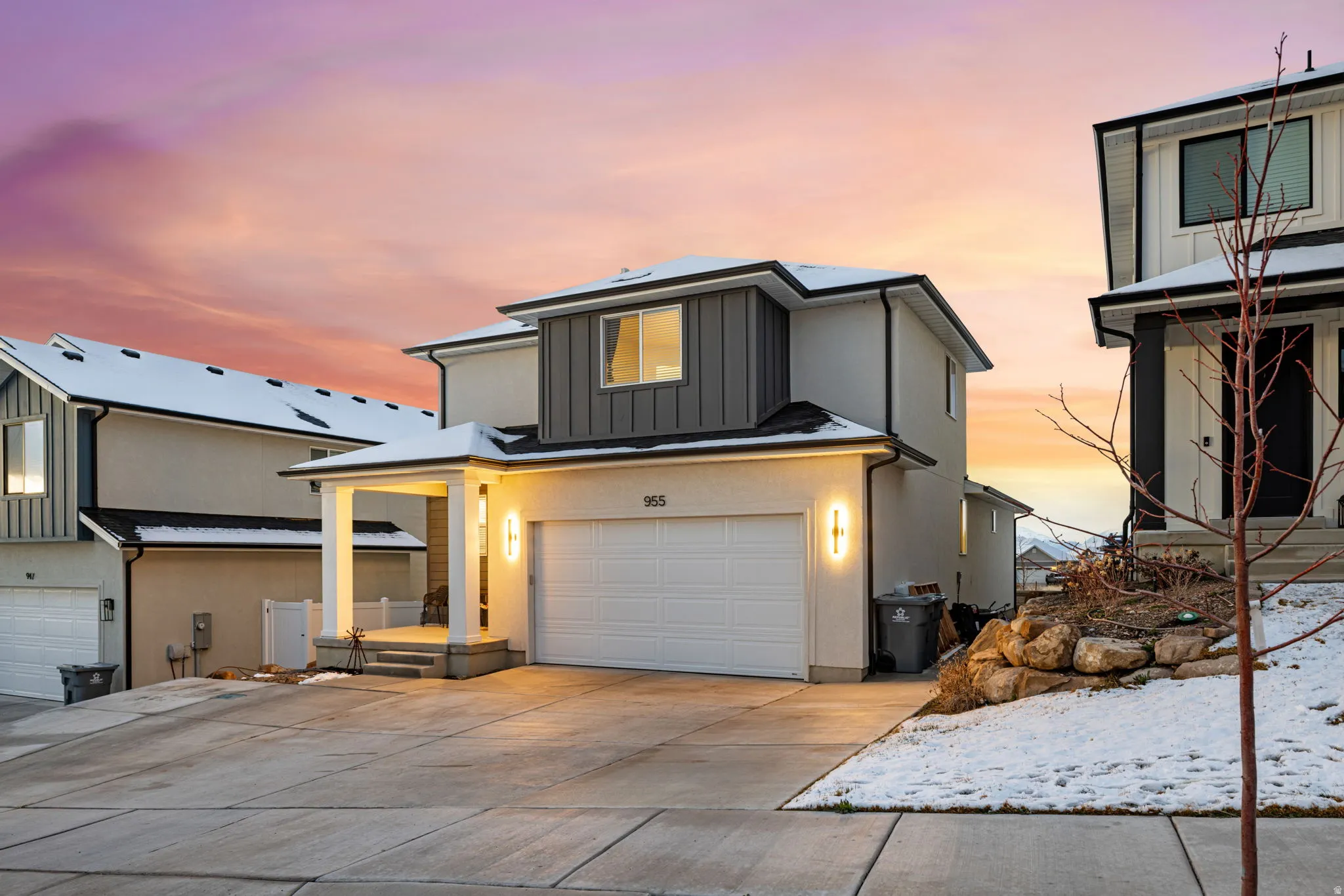 View of front of home with an attached garage, board and batten siding, concrete driveway, and roof mounted solar panels
