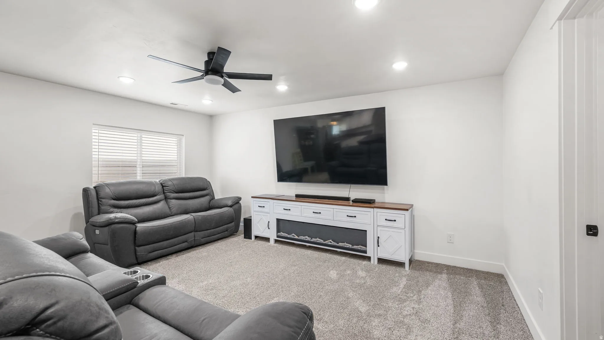 Living area with light colored carpet, ceiling fan, and recessed lighting
