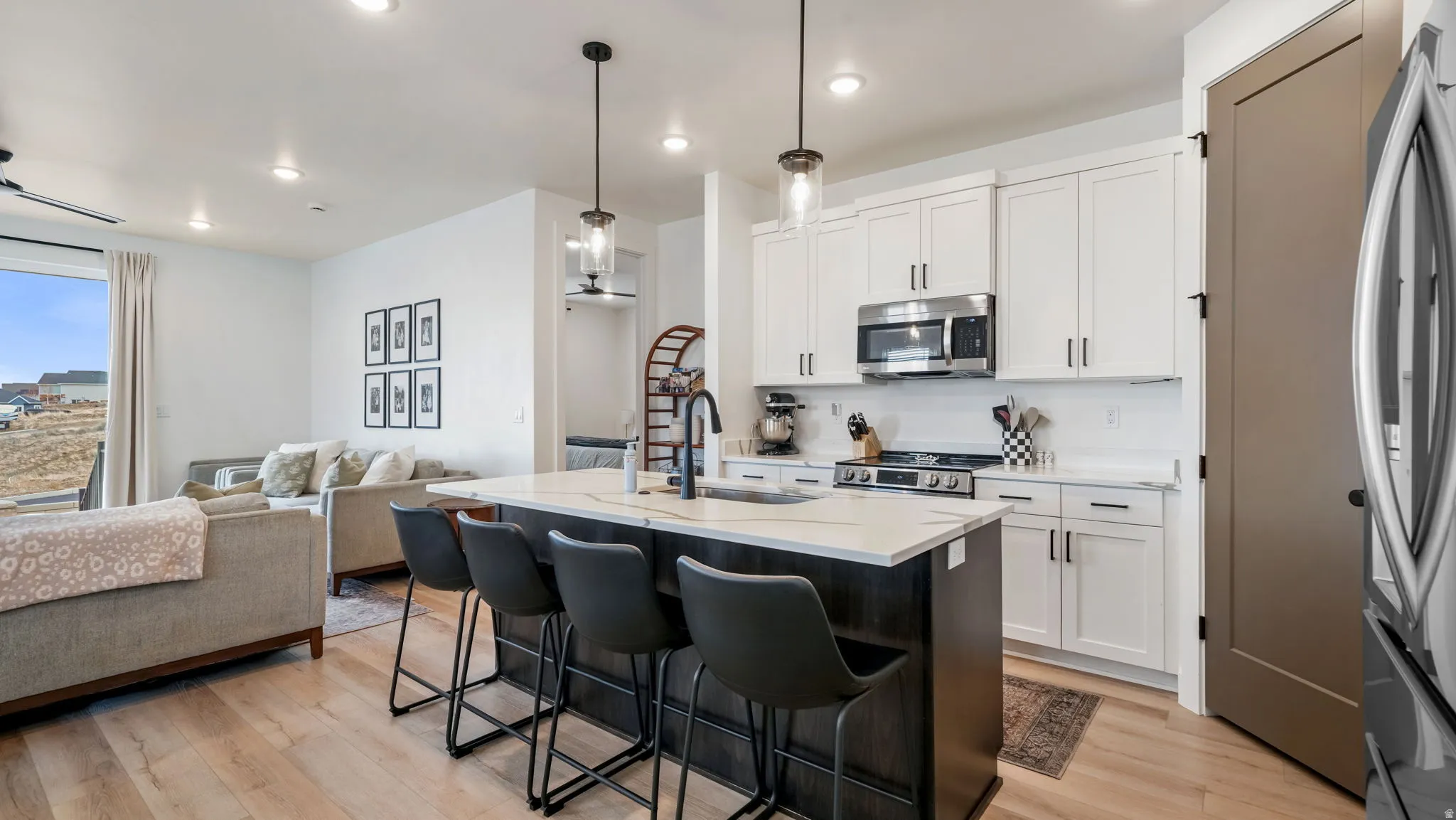 Kitchen featuring open floor plan, a kitchen bar, a center island with sink, stainless steel appliances, and pendant lighting