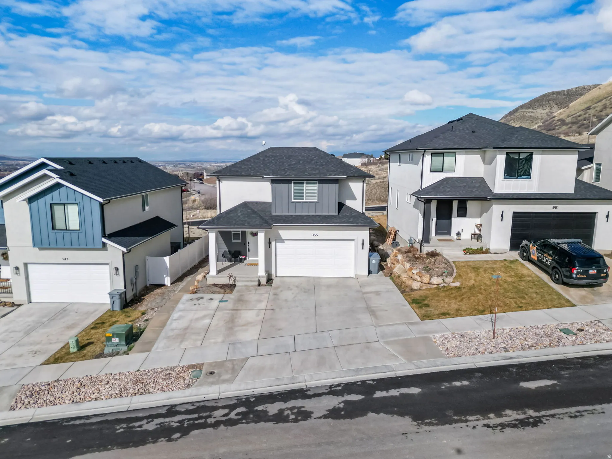 View of front of house featuring board and batten siding, a garage, concrete driveway, a shingled roof, and a mountain view