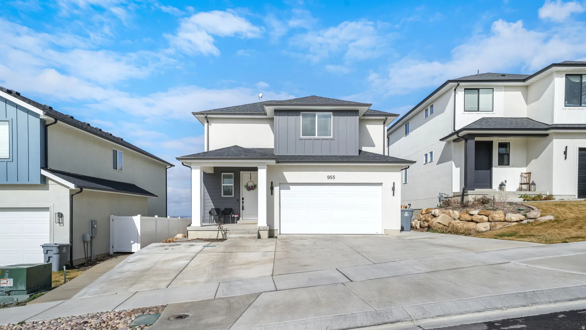 Traditional-style house featuring a shingled roof, board and batten siding, an attached garage, driveway, and covered porch