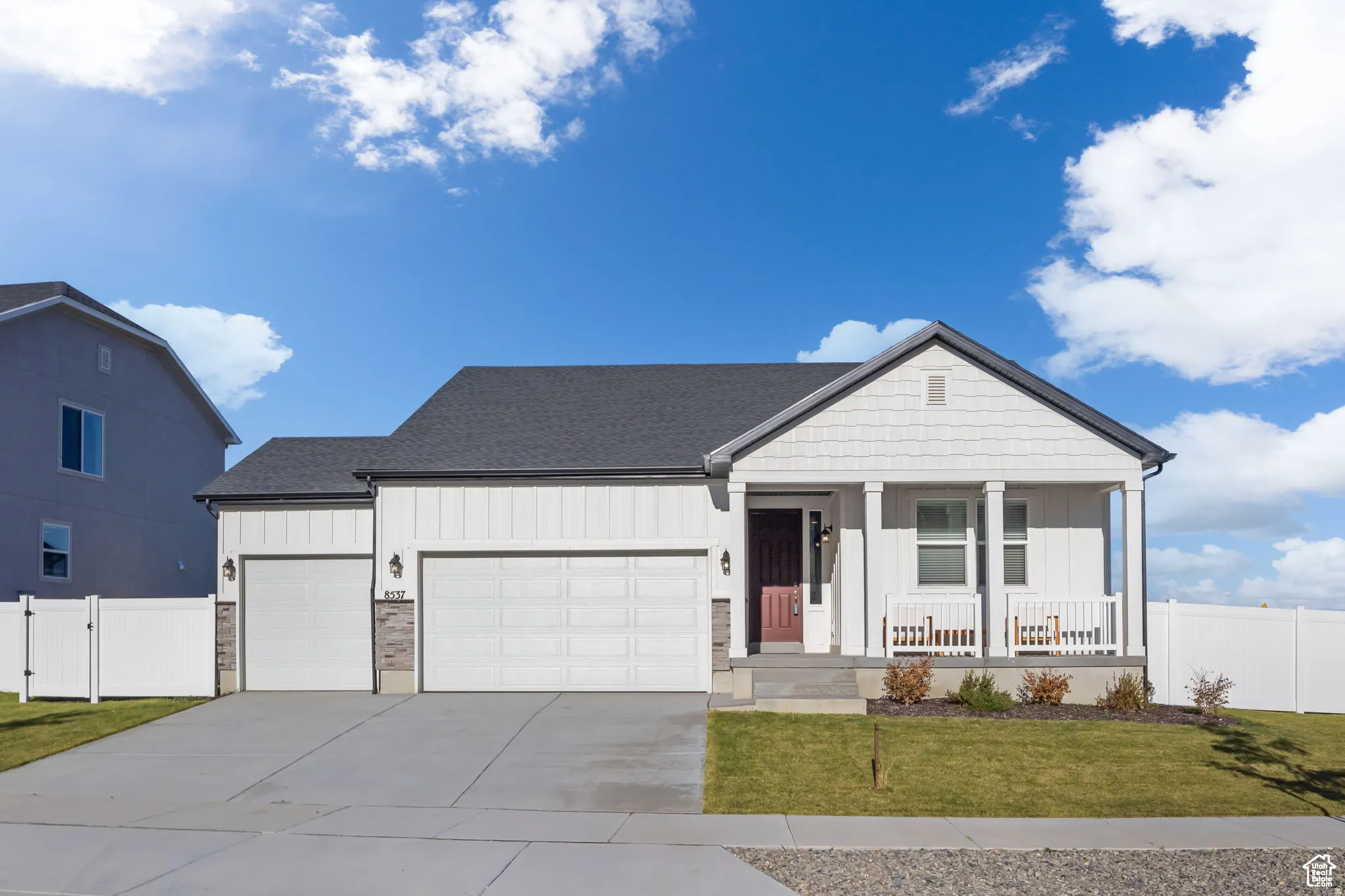 View of front of house with board and batten siding, a garage, covered porch, and concrete driveway