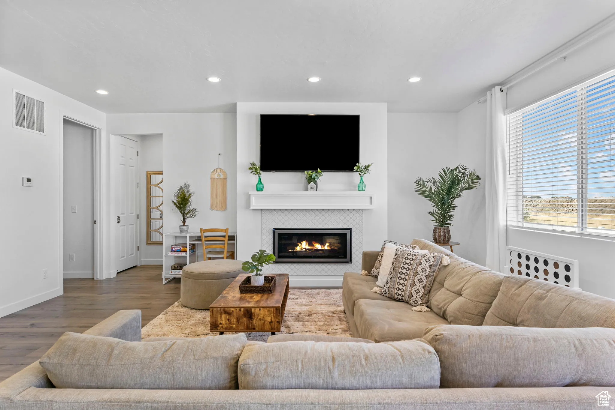 Living room with wood finished floors, a tile fireplace, and recessed lighting