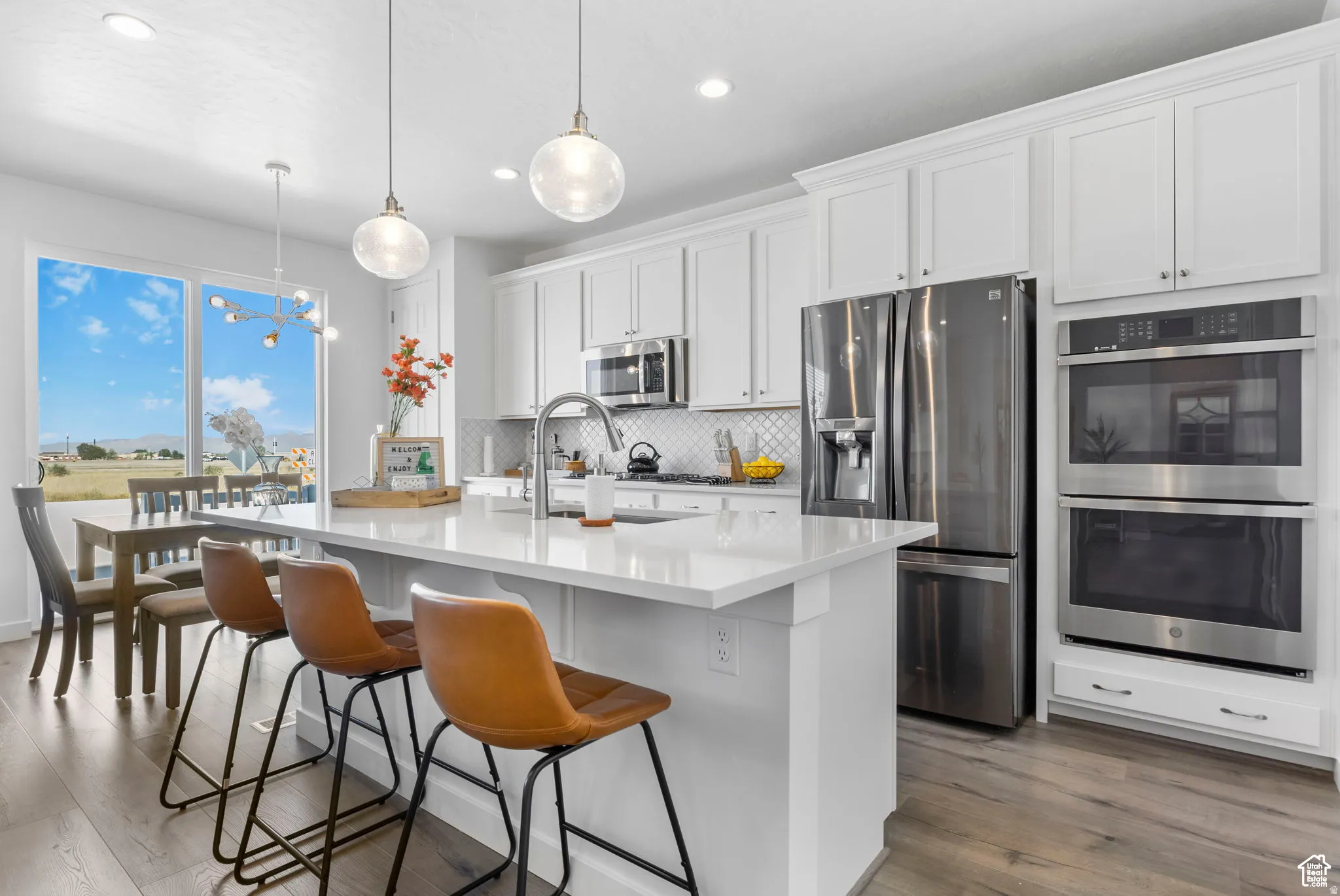 Kitchen with stainless steel appliances, white cabinets, a center island with sink, a kitchen breakfast bar, and light stone countertops