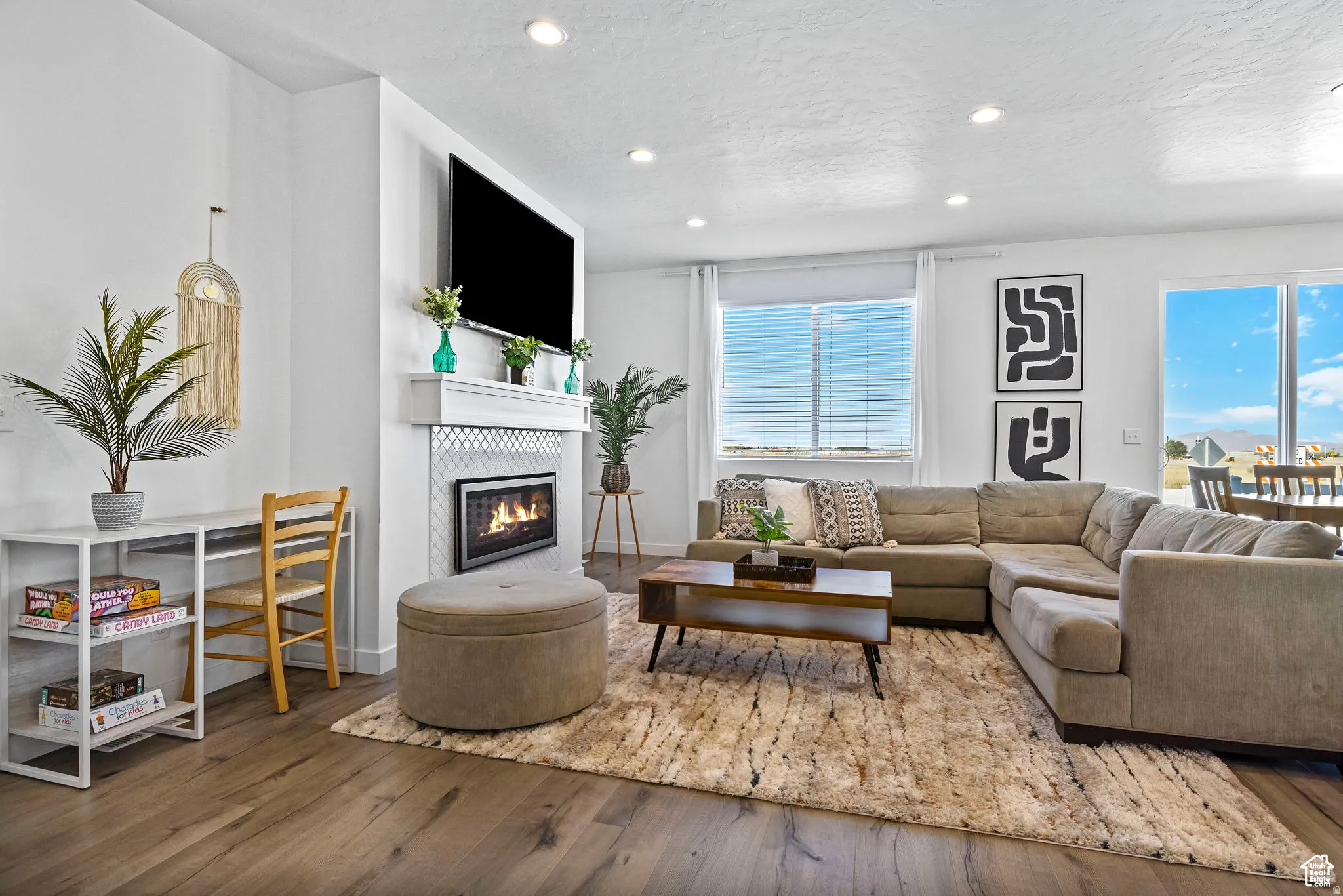 Living room with hardwood / wood-style floors, a glass covered fireplace, recessed lighting, and a textured ceiling