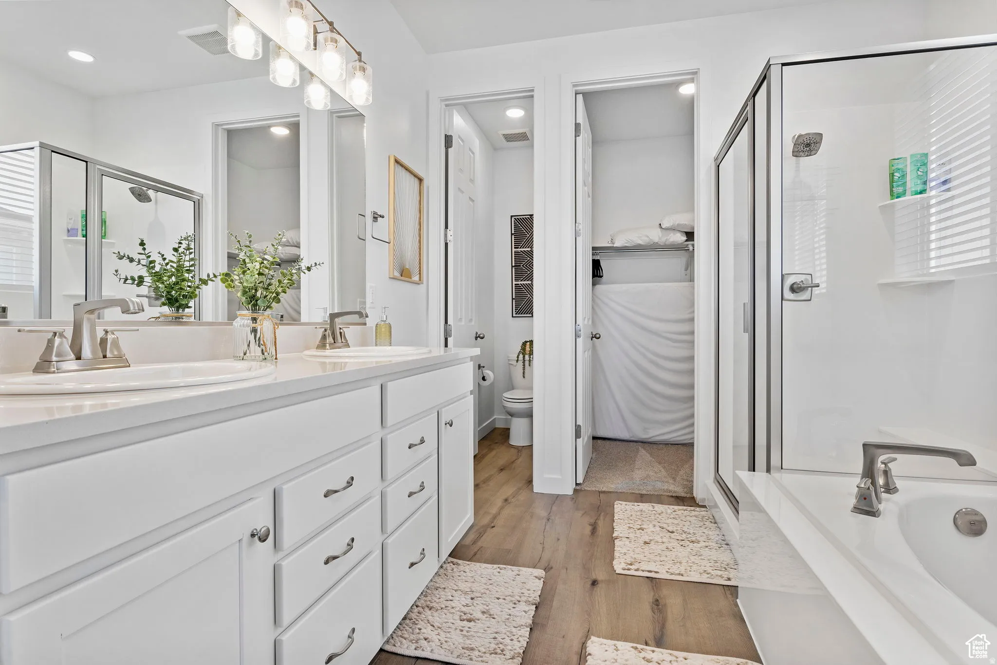 Full bath with a stall shower, double vanity, dark wood-type flooring, and a garden tub