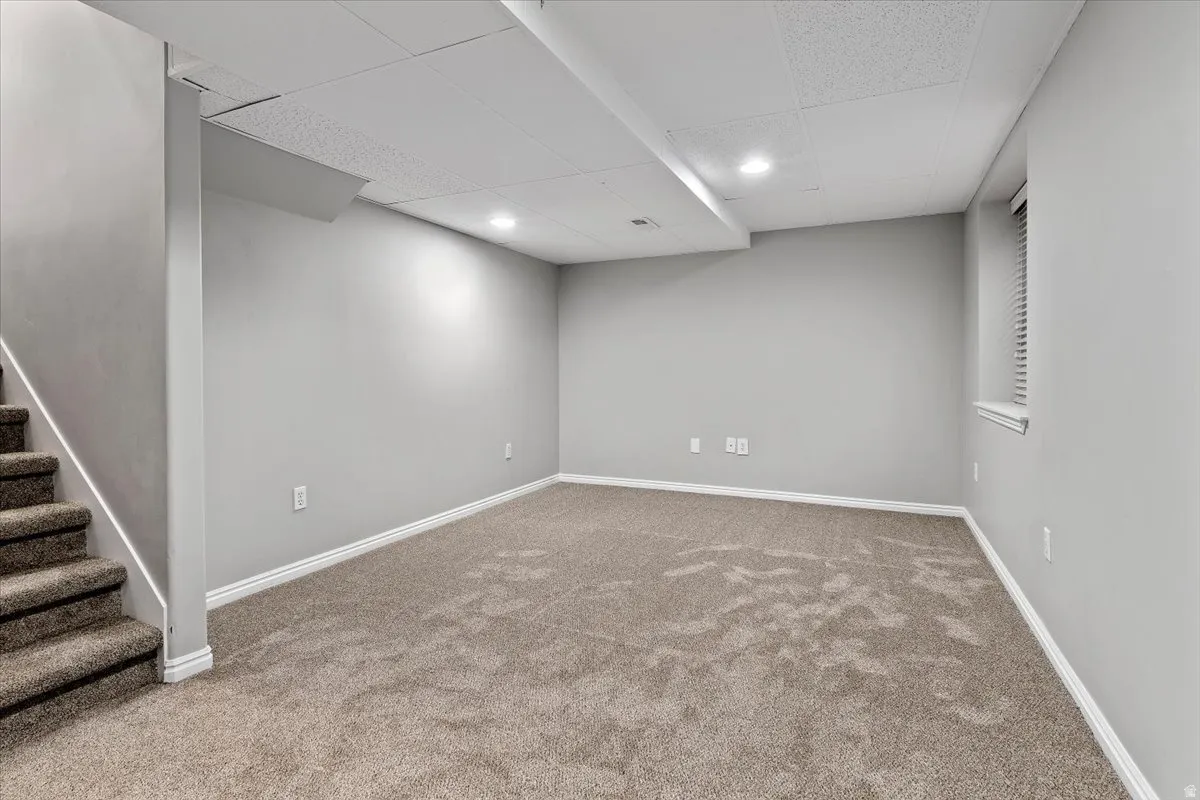 Finished below grade area featuring a paneled ceiling, carpet, and recessed lighting