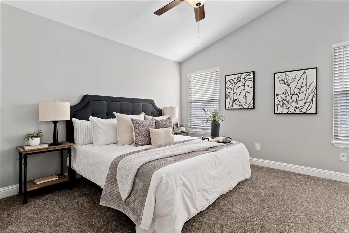 Carpeted bedroom with lofted ceiling and a ceiling fan