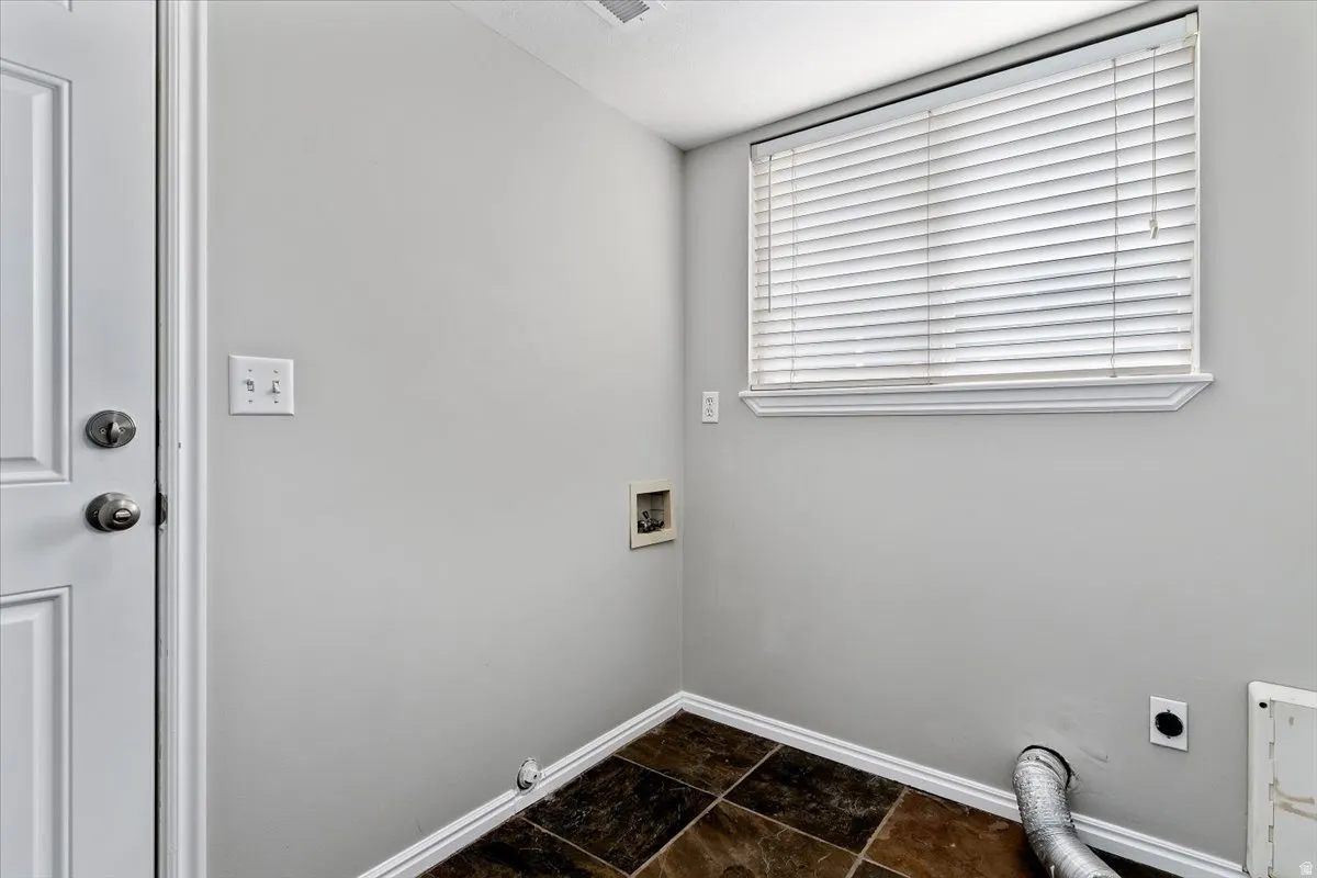 Laundry room with dark stone finish floors, hookup for an electric dryer, and hookup for a washing machine