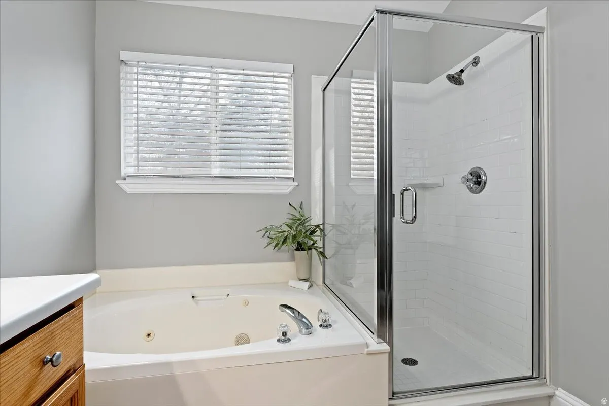 Bathroom featuring a stall shower, a tub with jets, and vanity