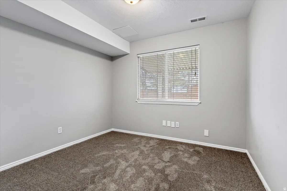 Spare room featuring dark colored carpet and baseboards