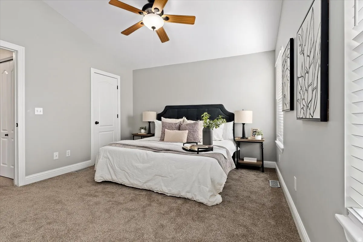 Bedroom with vaulted ceiling, carpet flooring, and a ceiling fan
