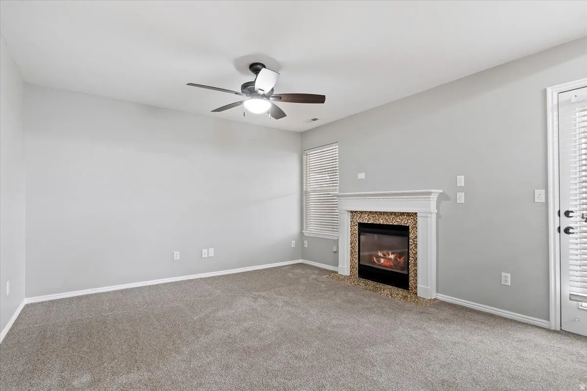 Unfurnished living room with ceiling fan, carpet floors, and a fireplace