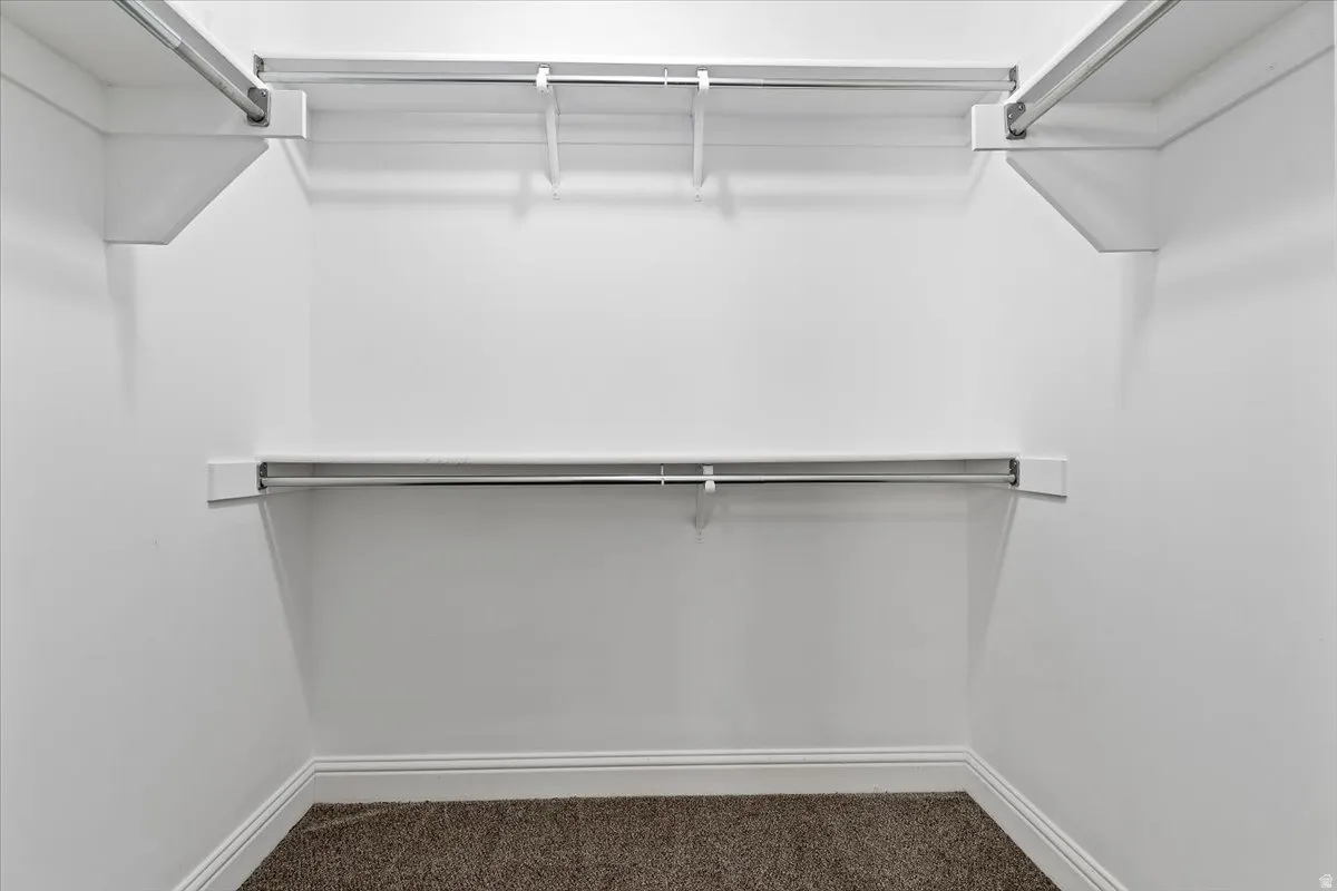 Walk in closet featuring dark carpet