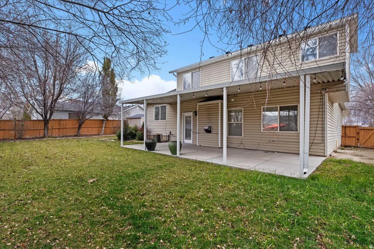 Rear view of house featuring a patio, a fenced backyard, and a gate