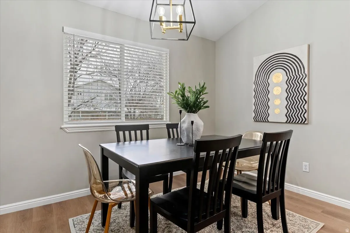 Dining room with light wood-style flooring, suspended lighting, and lofted ceiling