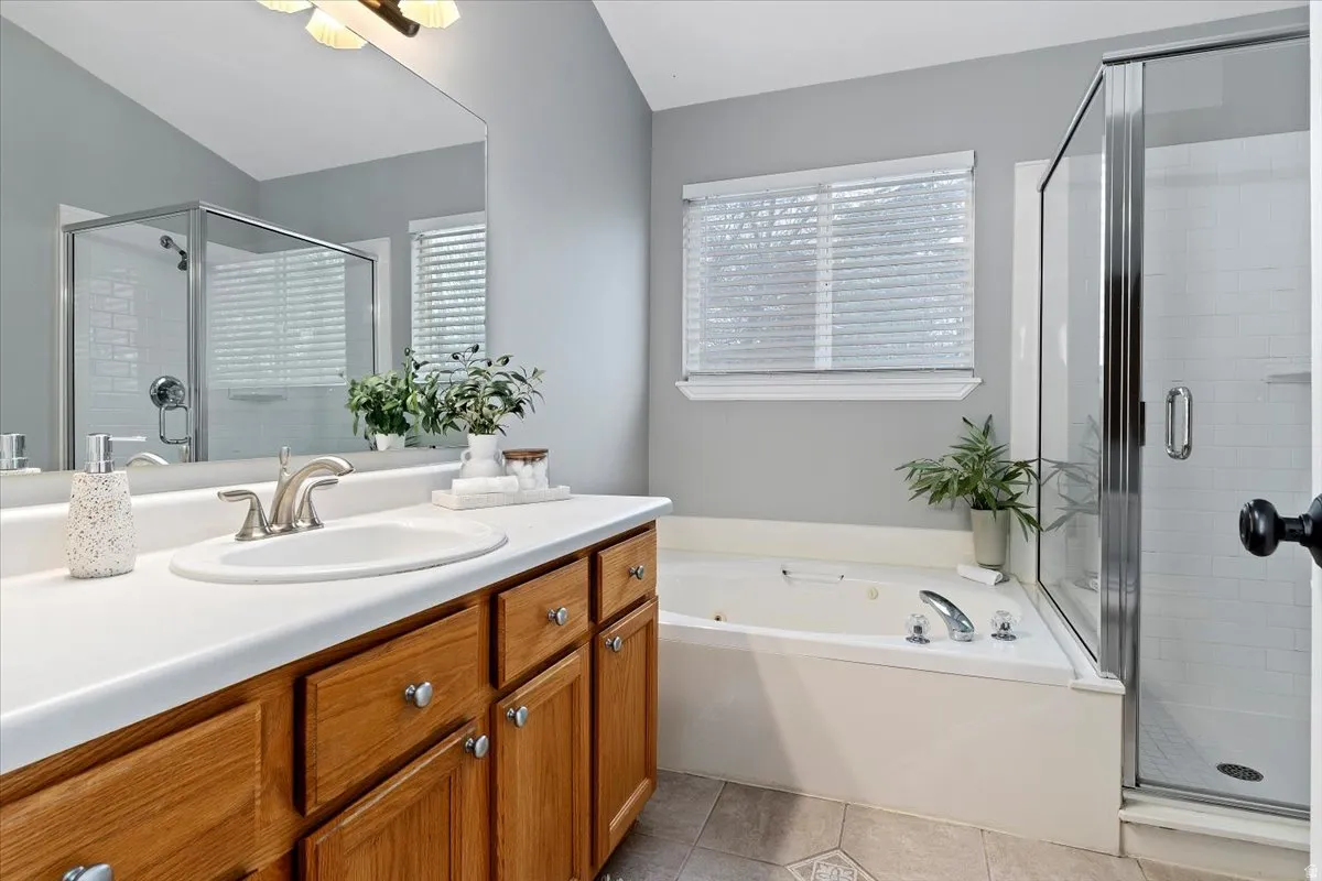 Full bath with a stall shower, vanity, a bath, healthy amount of natural light, and vaulted ceiling
