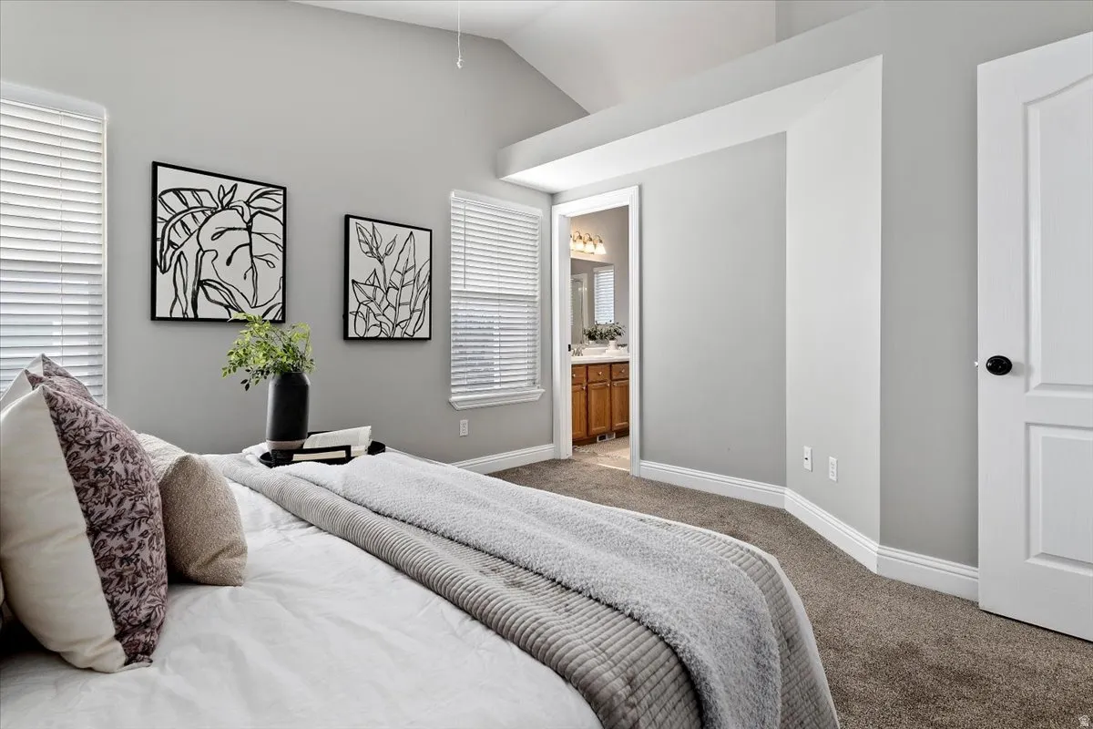 Carpeted bedroom with ensuite bathroom and lofted ceiling