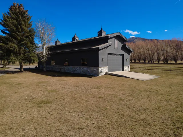 View of property exterior featuring stone siding, driveway, and a mountain view