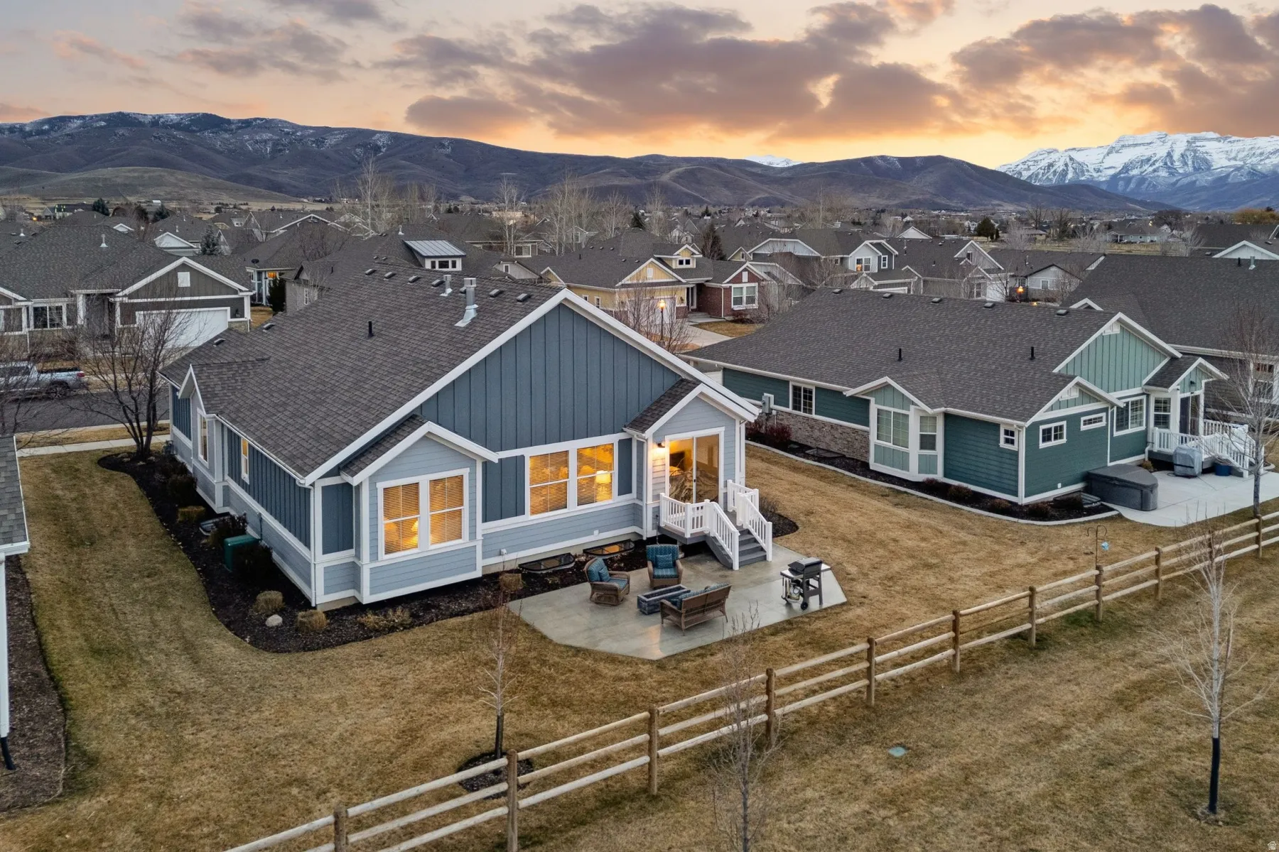 Back of house at dusk featuring a patio area, a fenced backyard, a mountain view, and a shingled roof