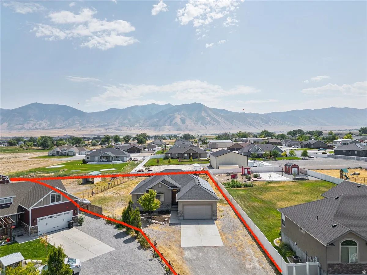 Aerial view of residential area with property parcel outlined and a mountain backdrop