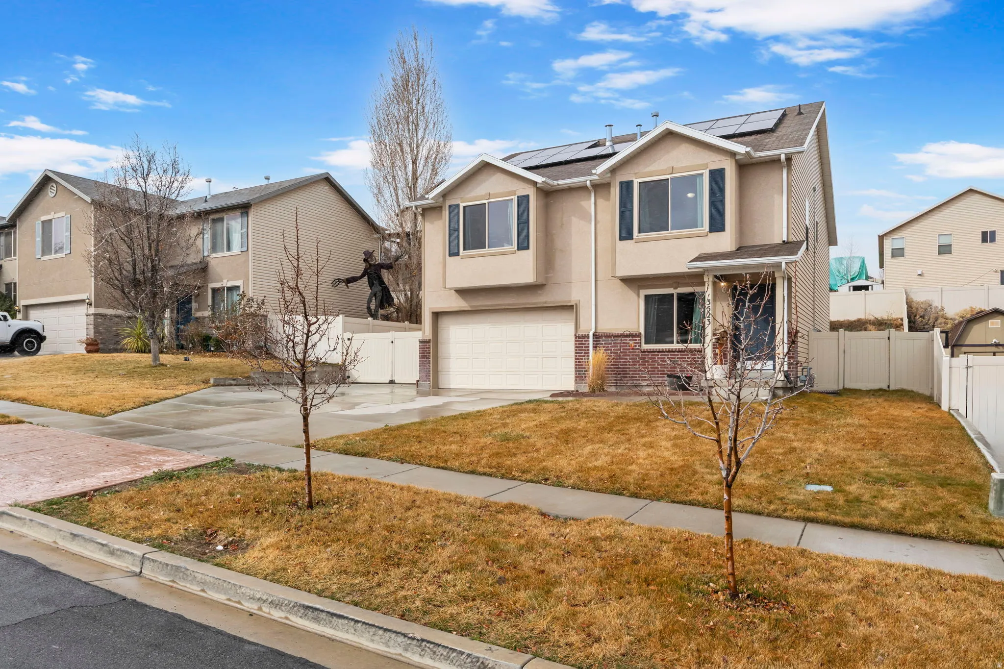 Traditional home featuring a gate, stucco siding, concrete driveway, an attached garage, and roof mounted solar panels
