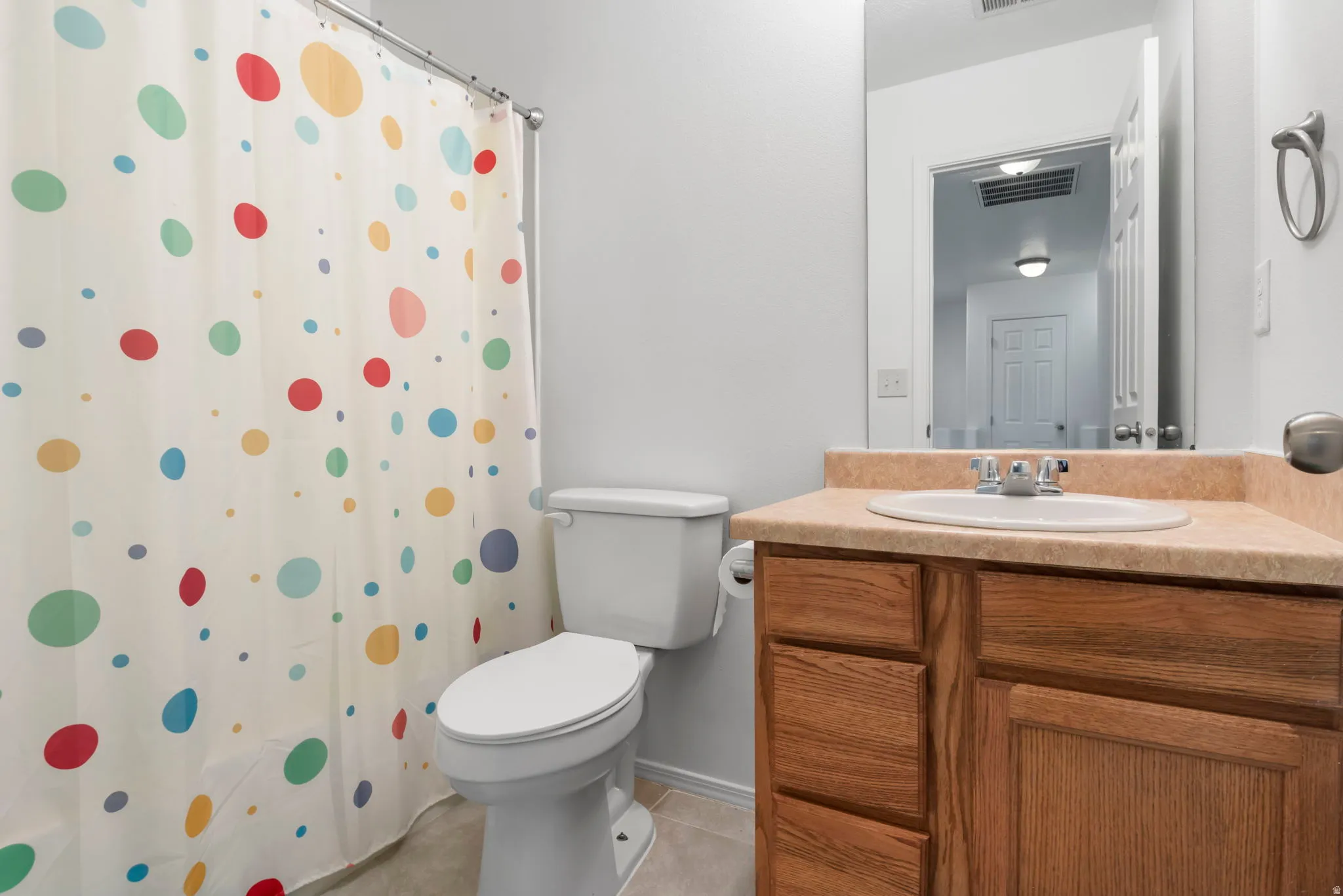 Bathroom with vanity, a shower with shower curtain, and light tile patterned flooring