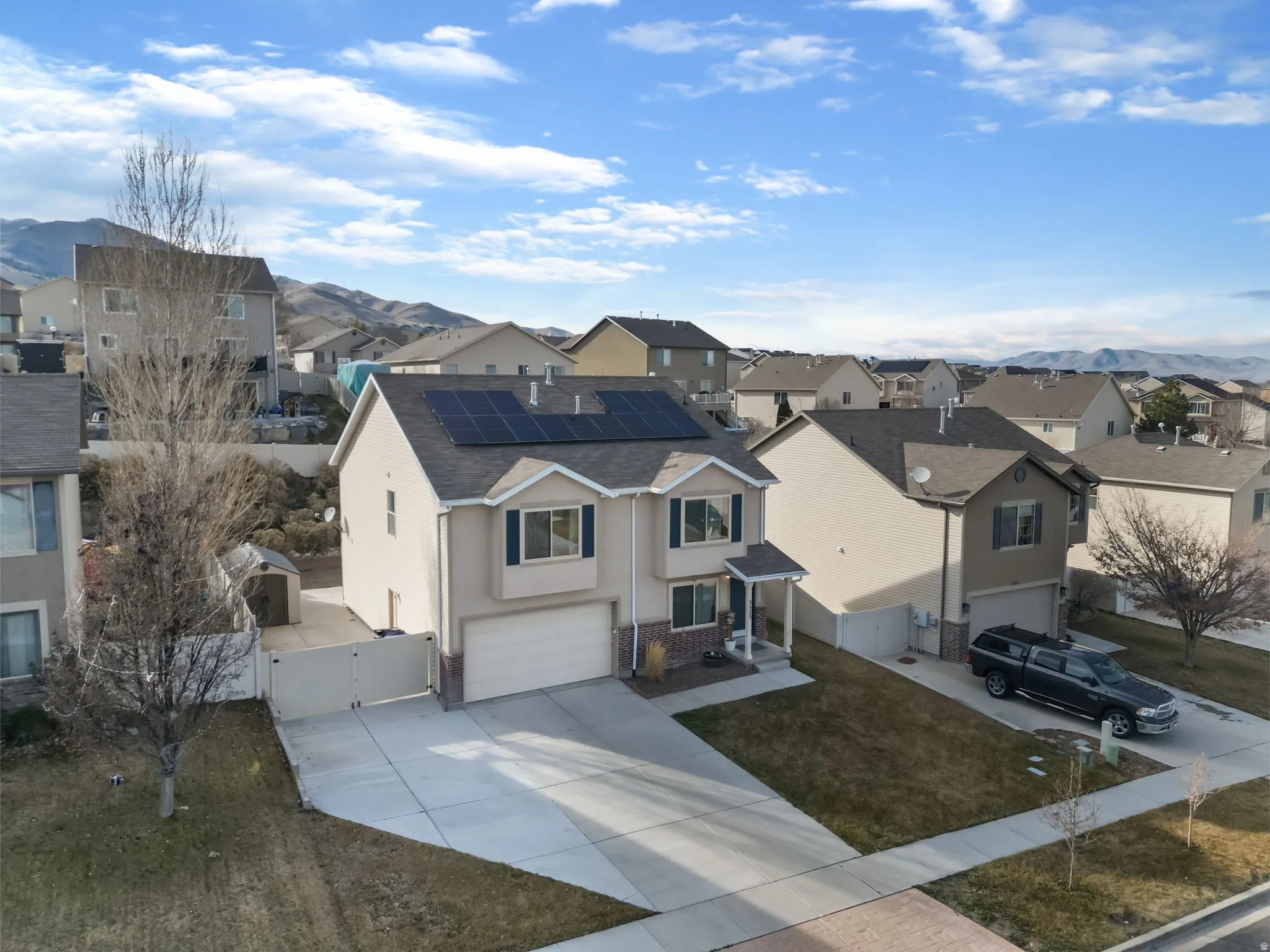 View of front of house featuring a gate, solar panels, an attached garage, a residential view, and concrete driveway