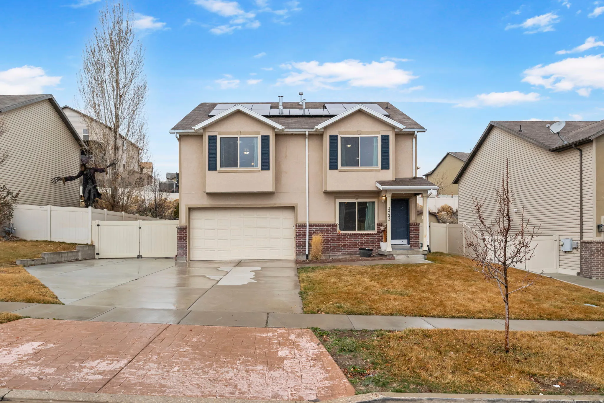 Traditional home with solar panels, stucco siding, a gate, an attached garage, and driveway