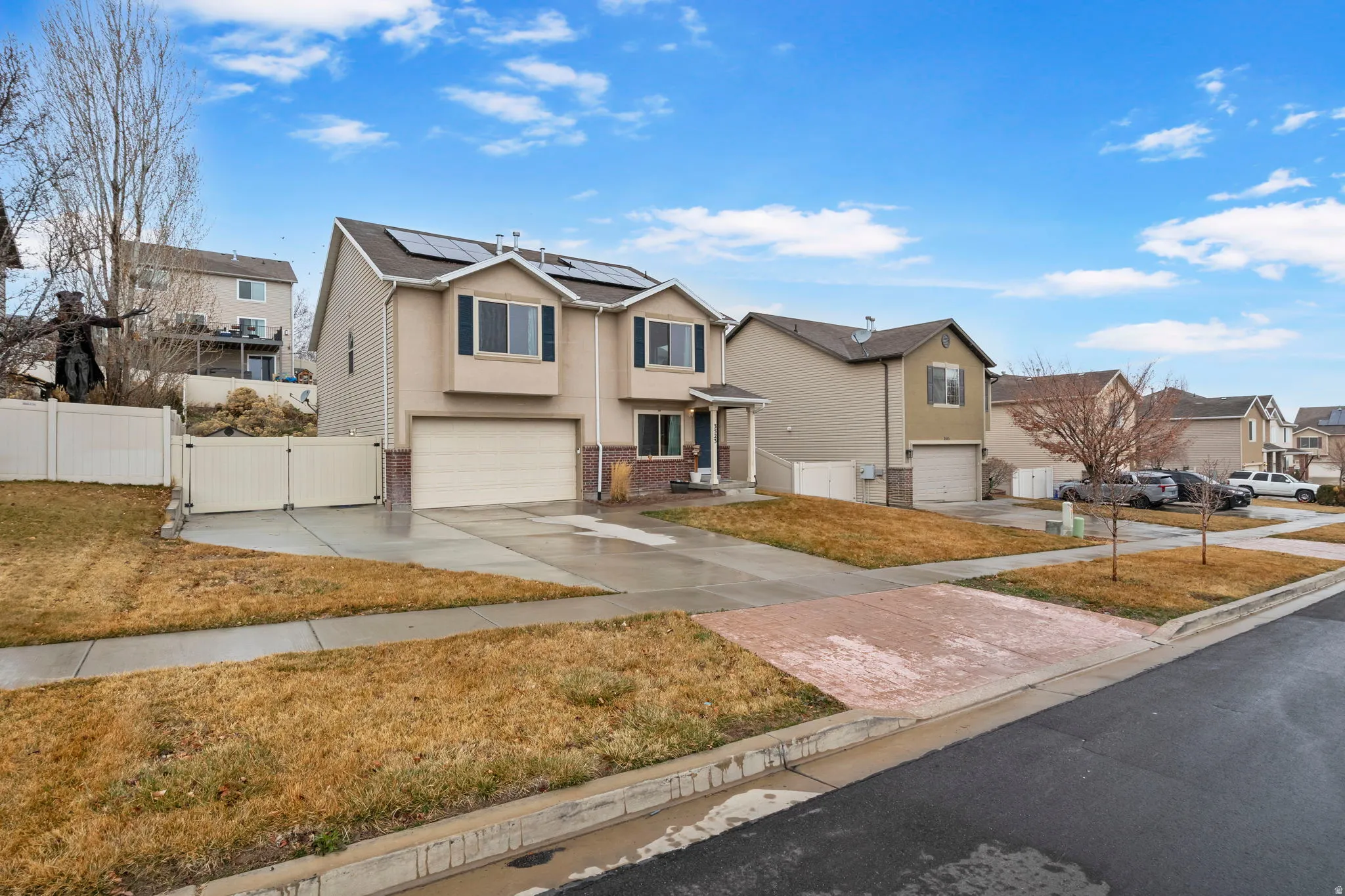 Traditional home featuring a gate, a residential view, solar panels, an attached garage, and driveway