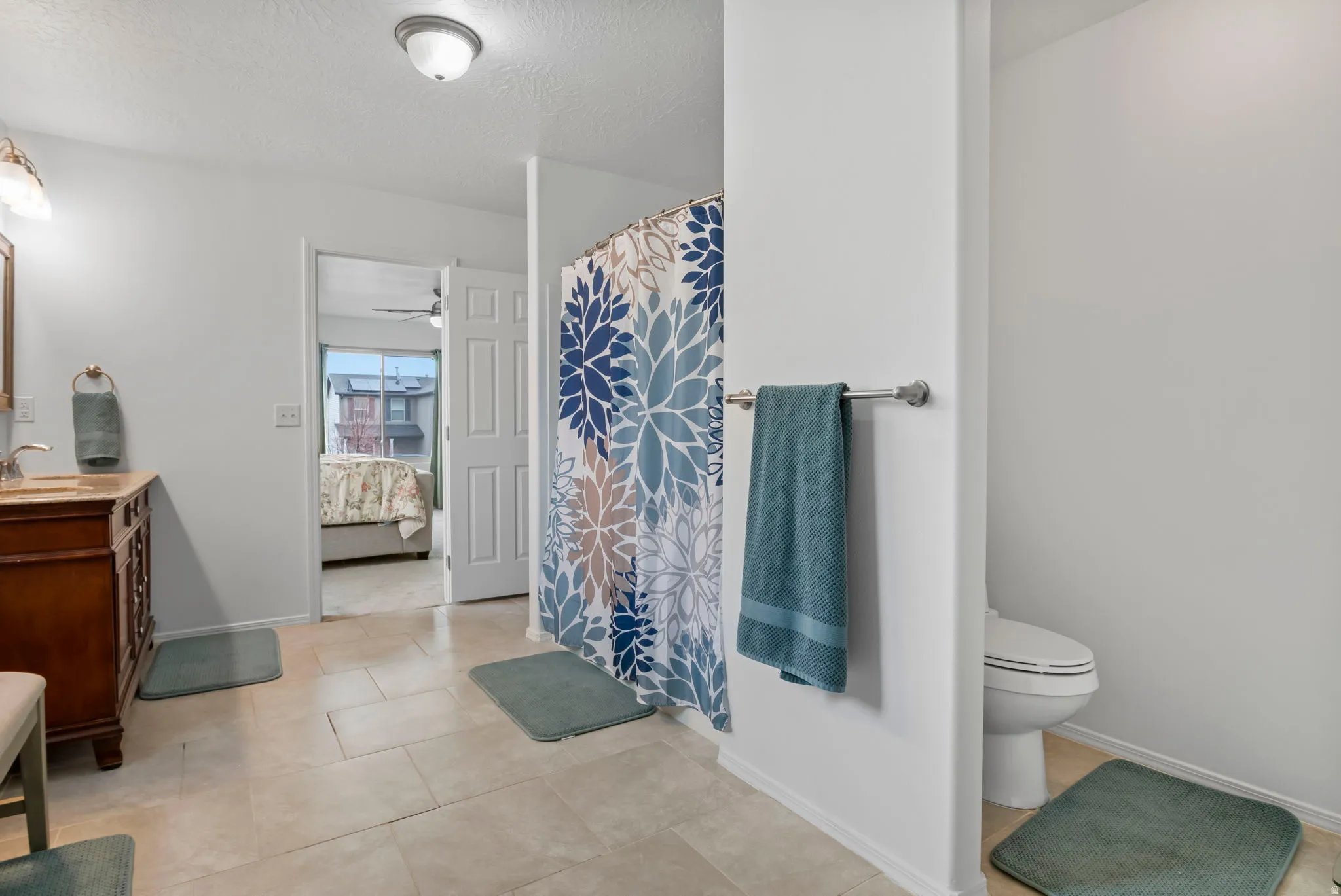 Full bathroom with vanity, connected bathroom, a shower with curtain, a textured ceiling, and light tile patterned flooring