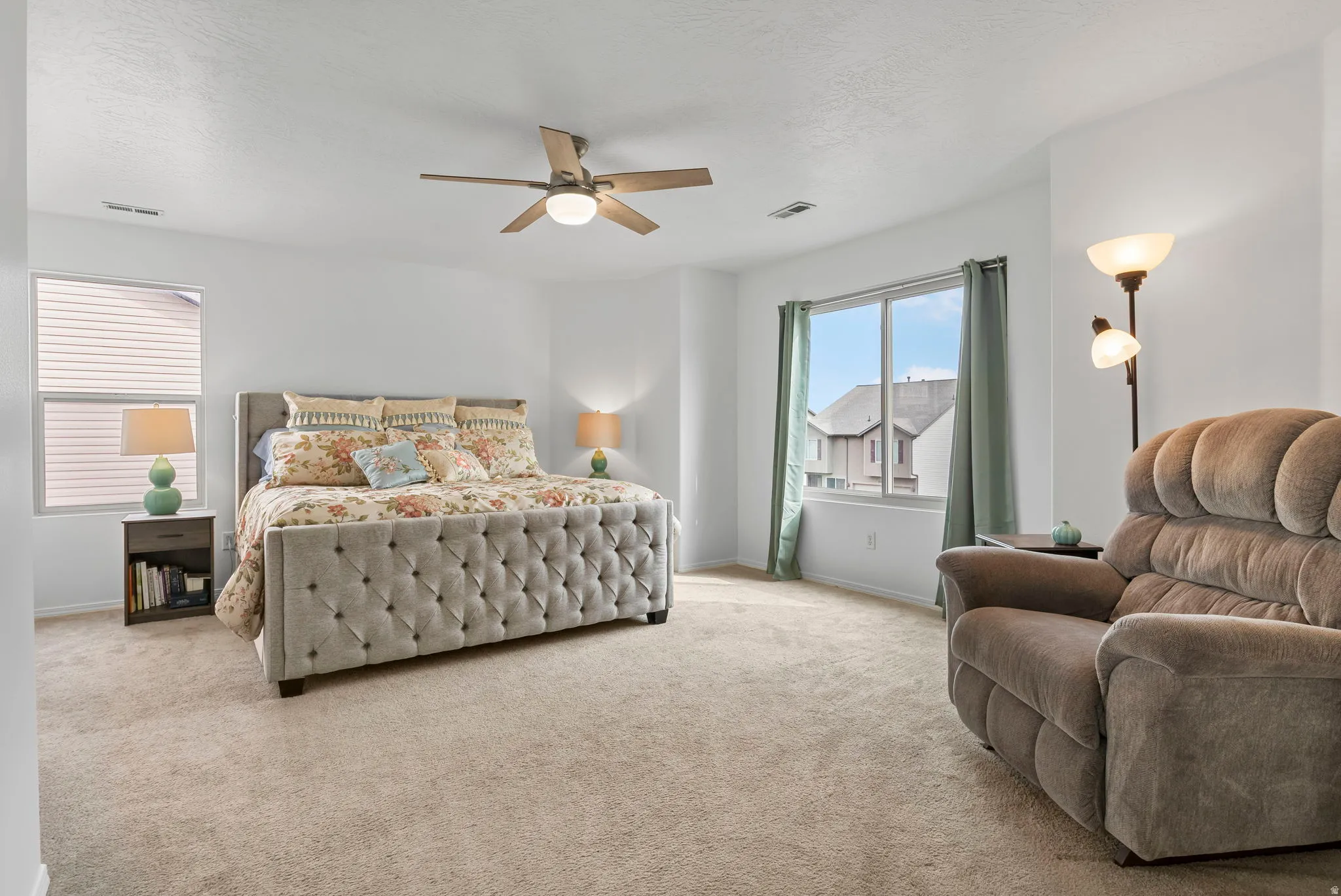 Bedroom with light colored carpet, a ceiling fan, and a textured ceiling