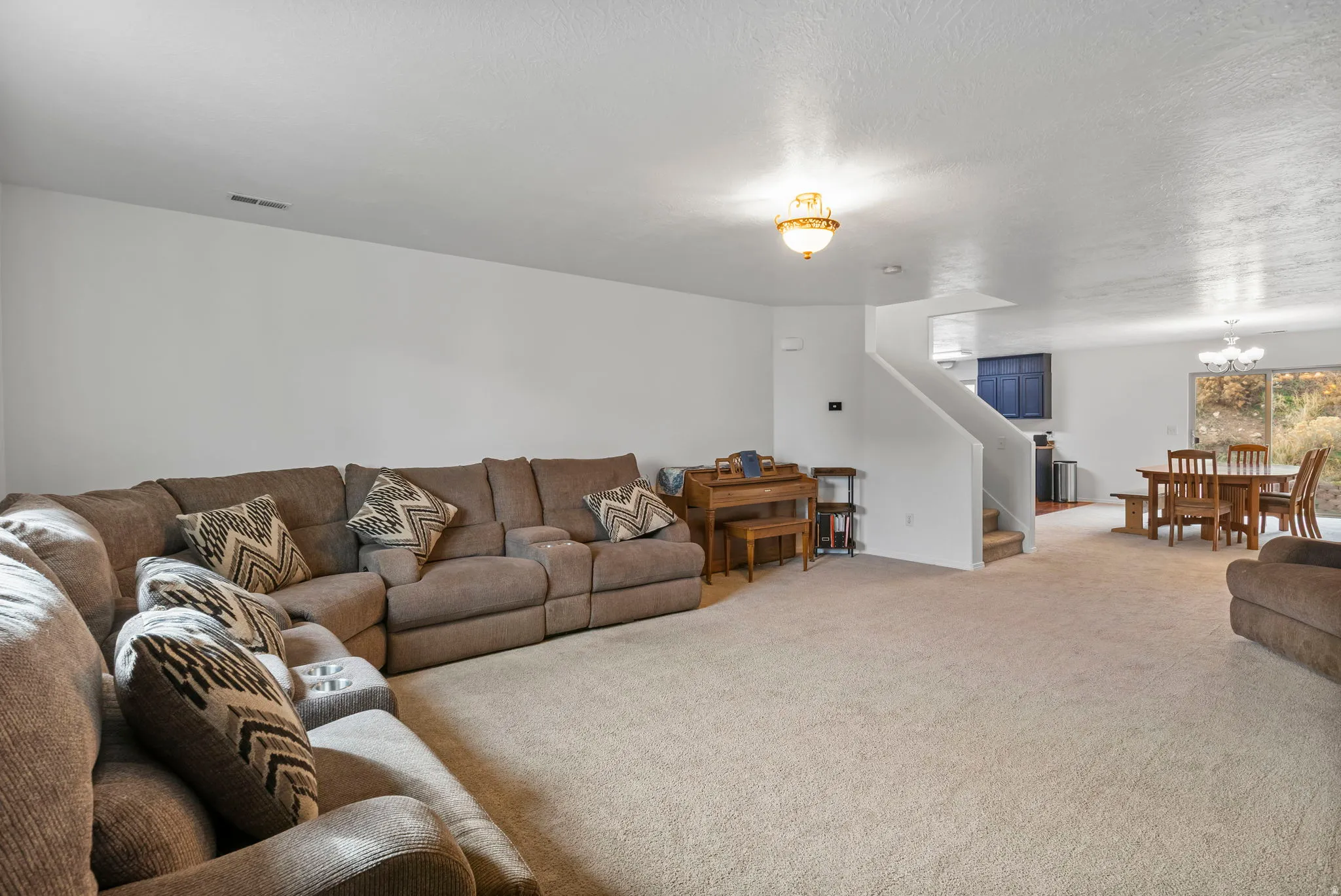 Carpeted living area featuring hanging lights and a textured ceiling