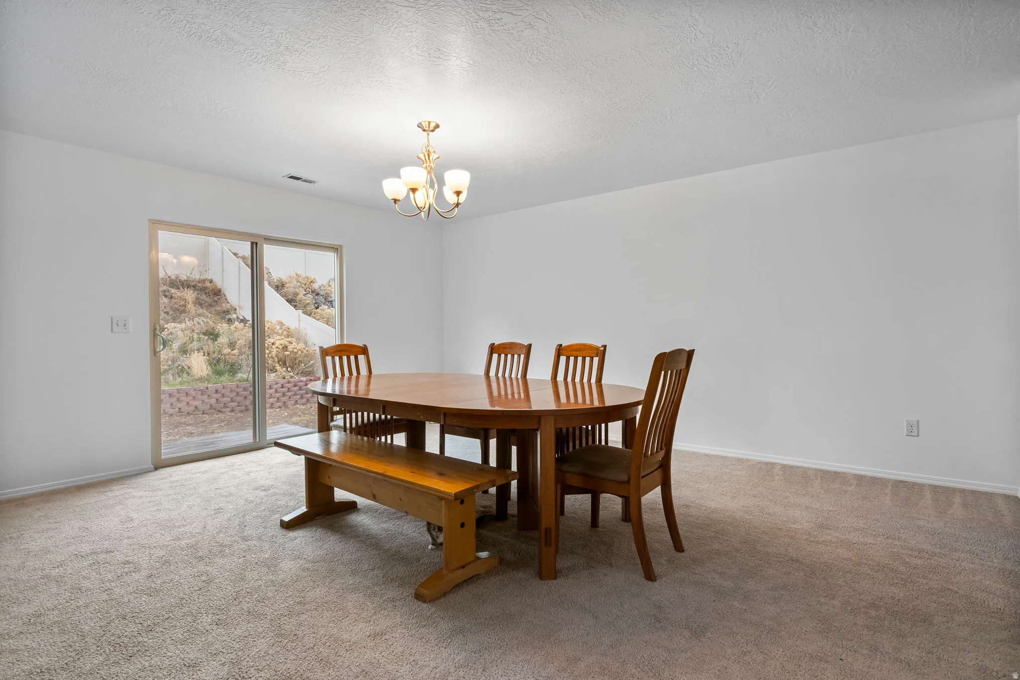Dining room with light colored carpet, a chandelier, and a textured ceiling