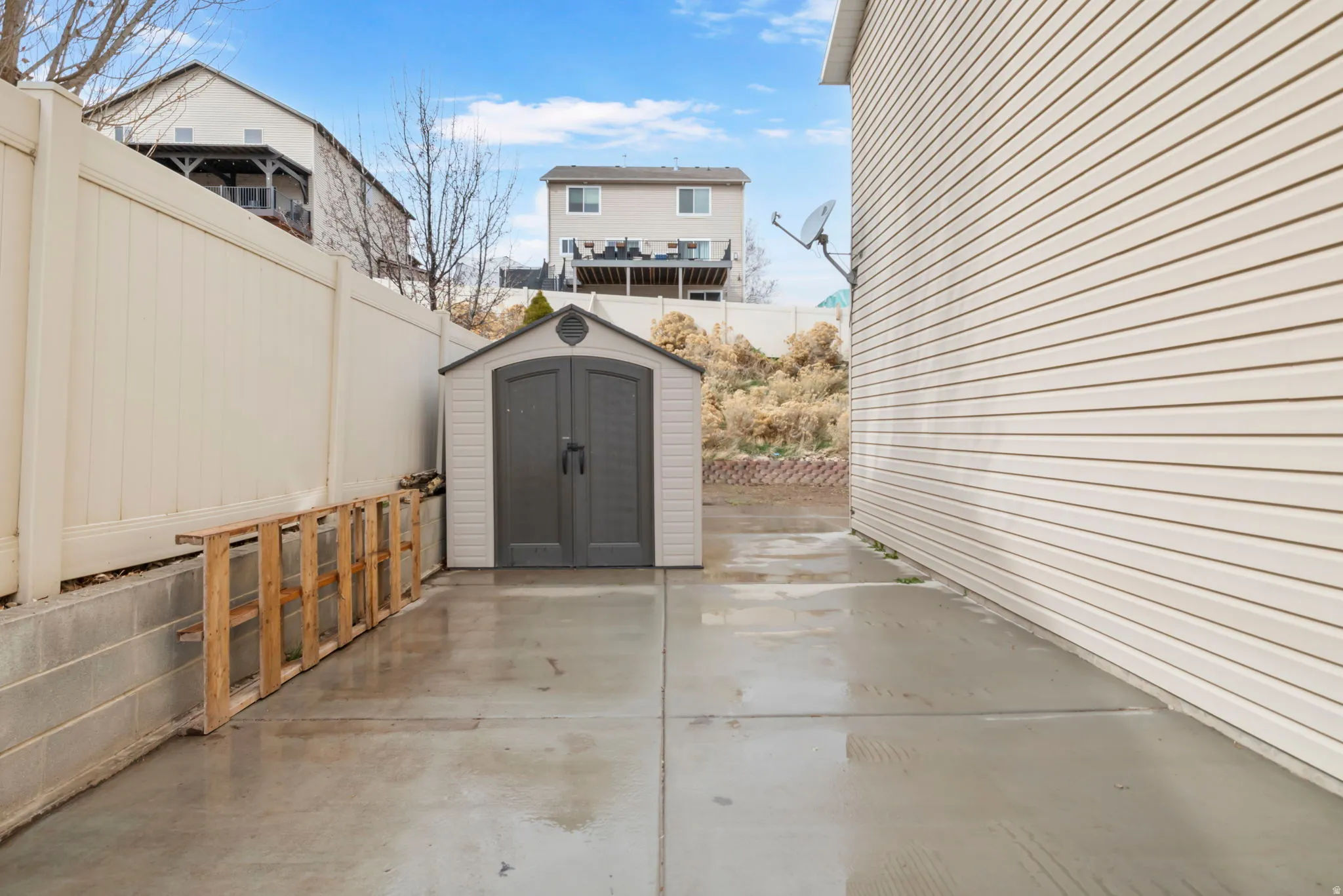 Fenced backyard featuring a storage unit and a patio
