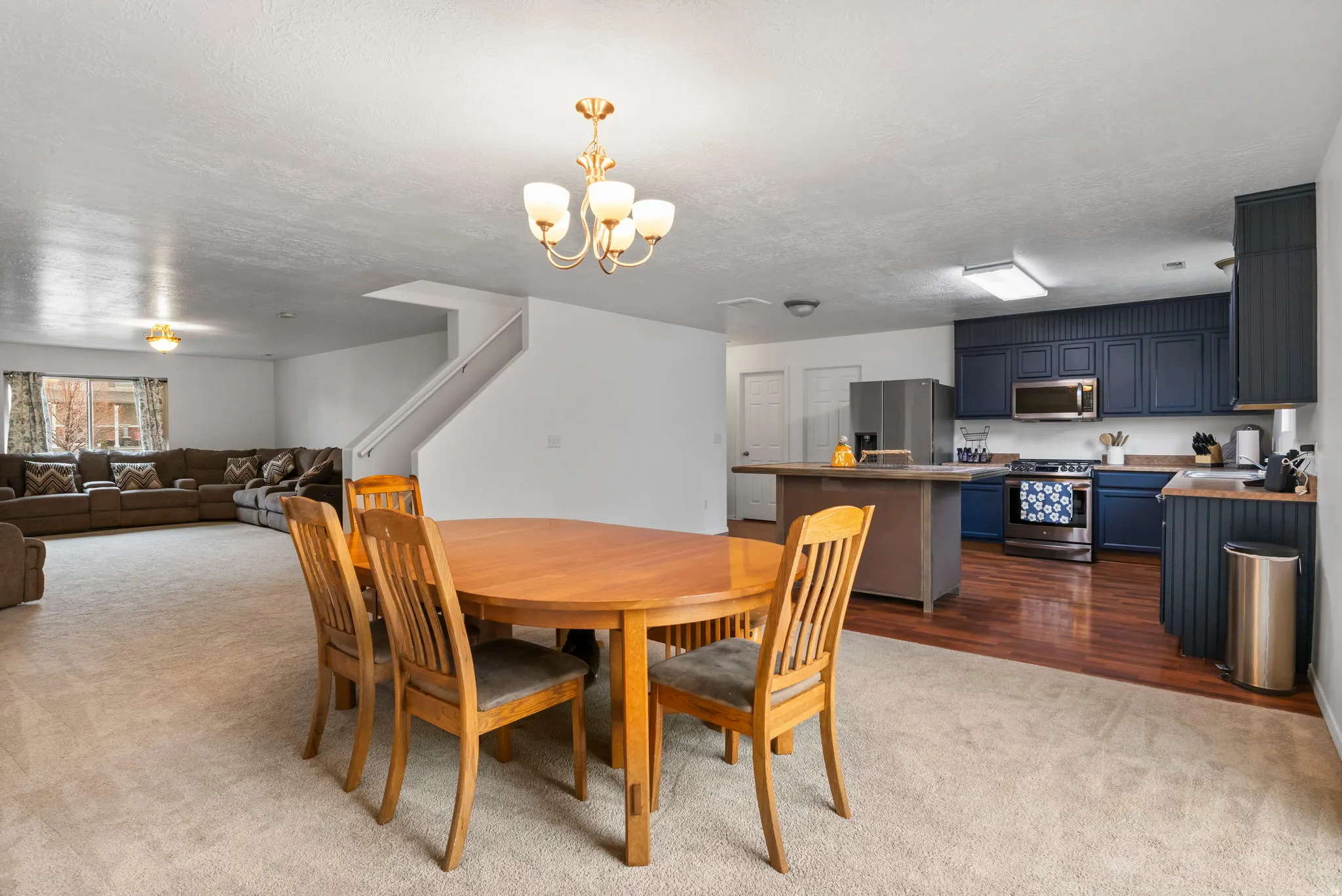 Dining area featuring dark colored carpet, hanging lights, and a textured ceiling