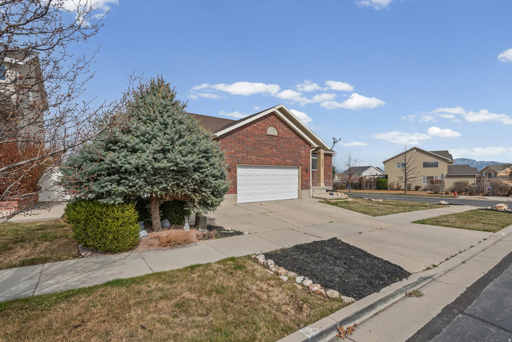 View of front facade featuring brick siding, driveway, an attached garage, and a front yard