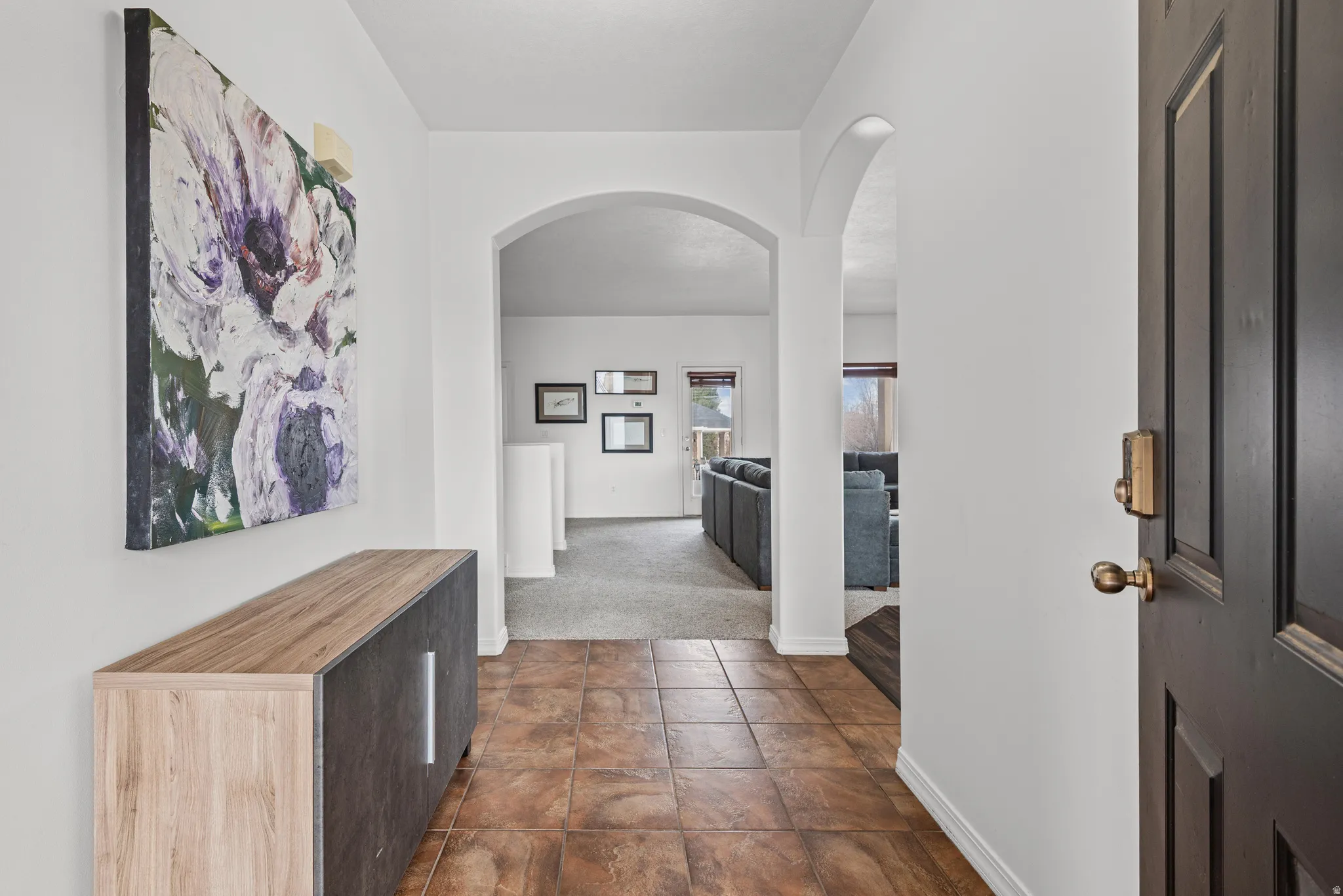 Entryway featuring arched walkways and dark colored carpet