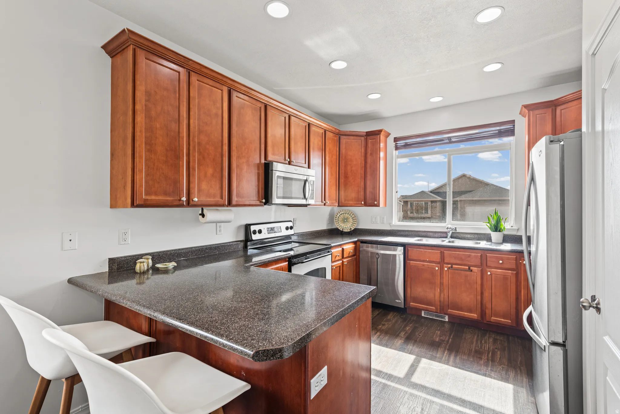 Kitchen featuring a breakfast bar, a peninsula, stainless steel appliances, dark wood-style flooring, and recessed lighting