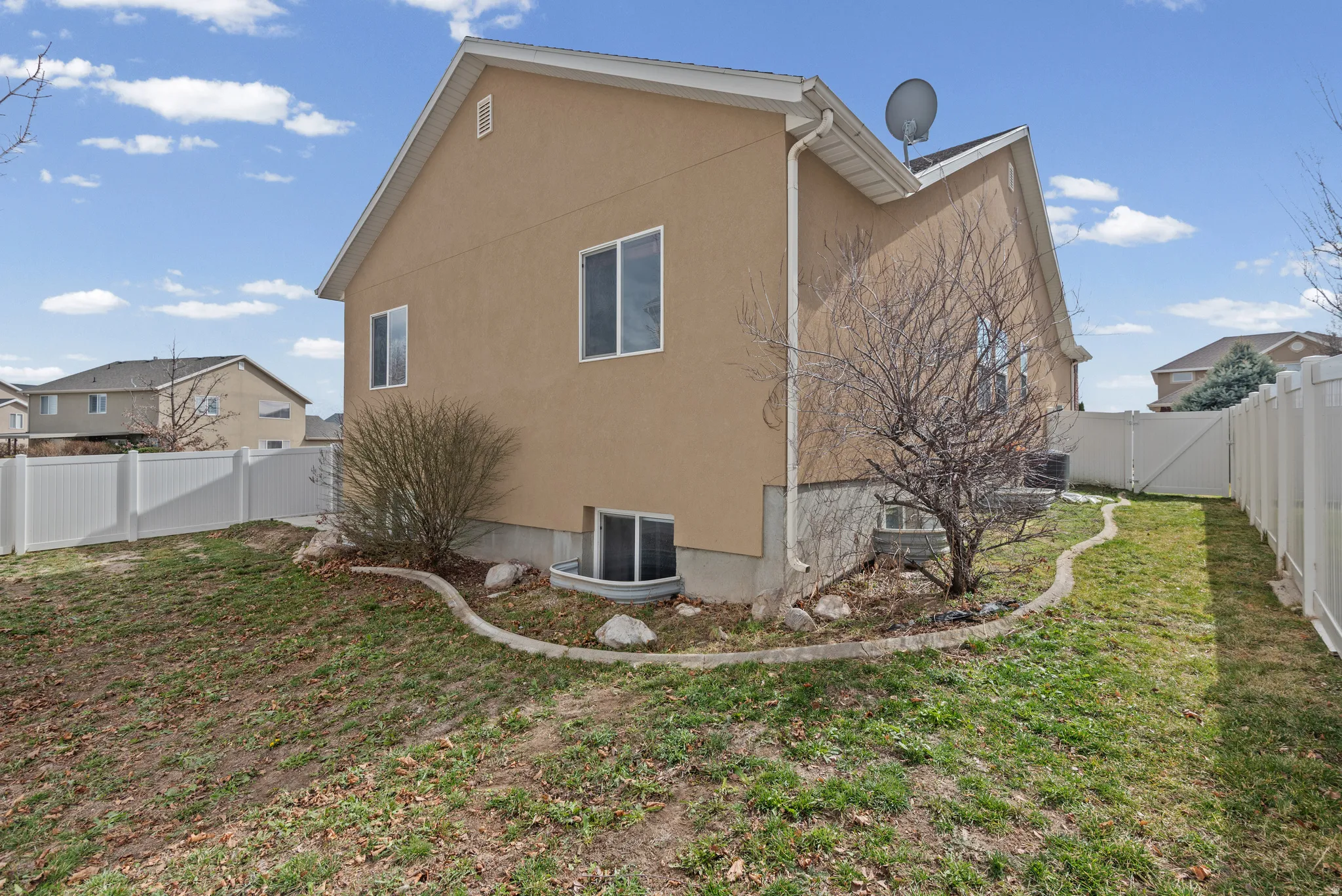 Back of property with a fenced backyard, stucco siding, and a gate