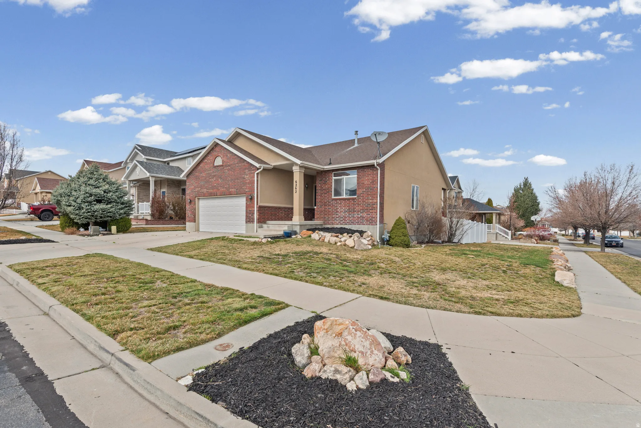 Single story home featuring concrete driveway, brick siding, a front lawn, a residential view, and a garage